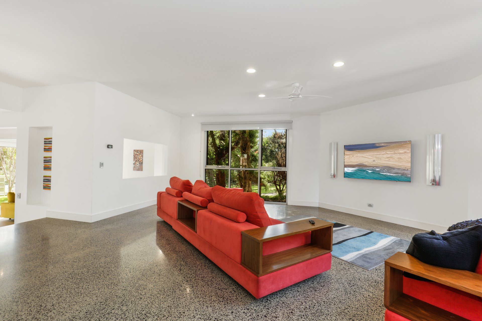 A living room with a red couch and a television on the wall.