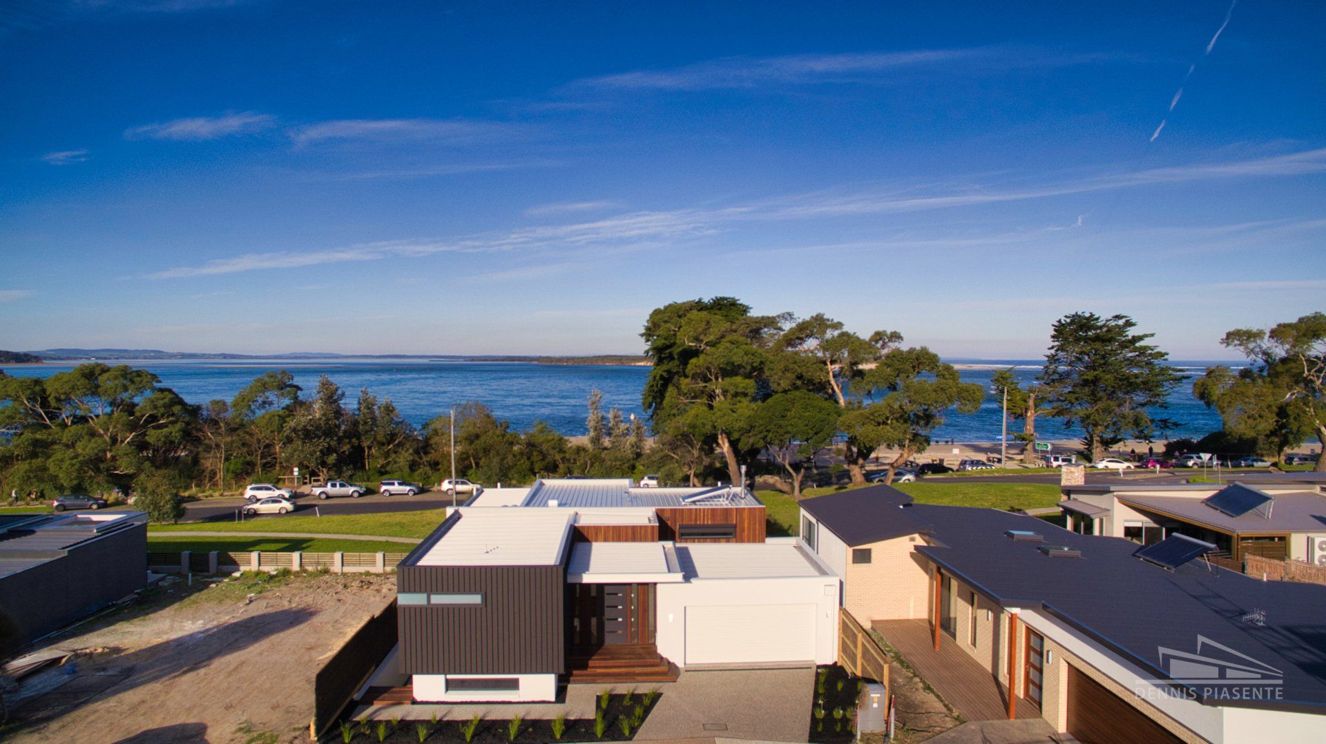 An aerial view of a modern house next to a body of water.