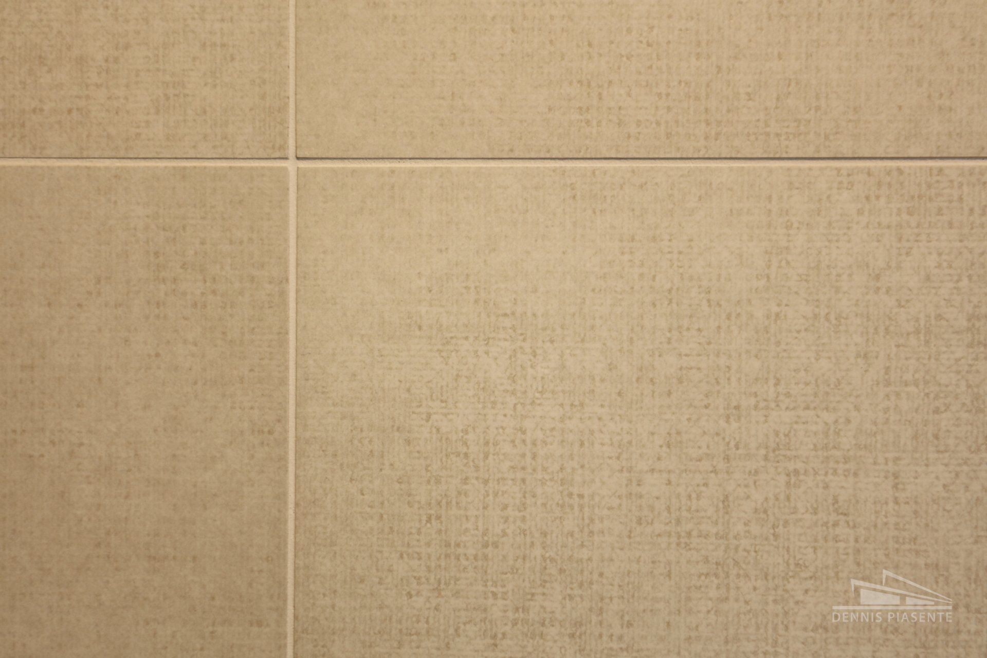 A close up of a beige tile wall with white grout.