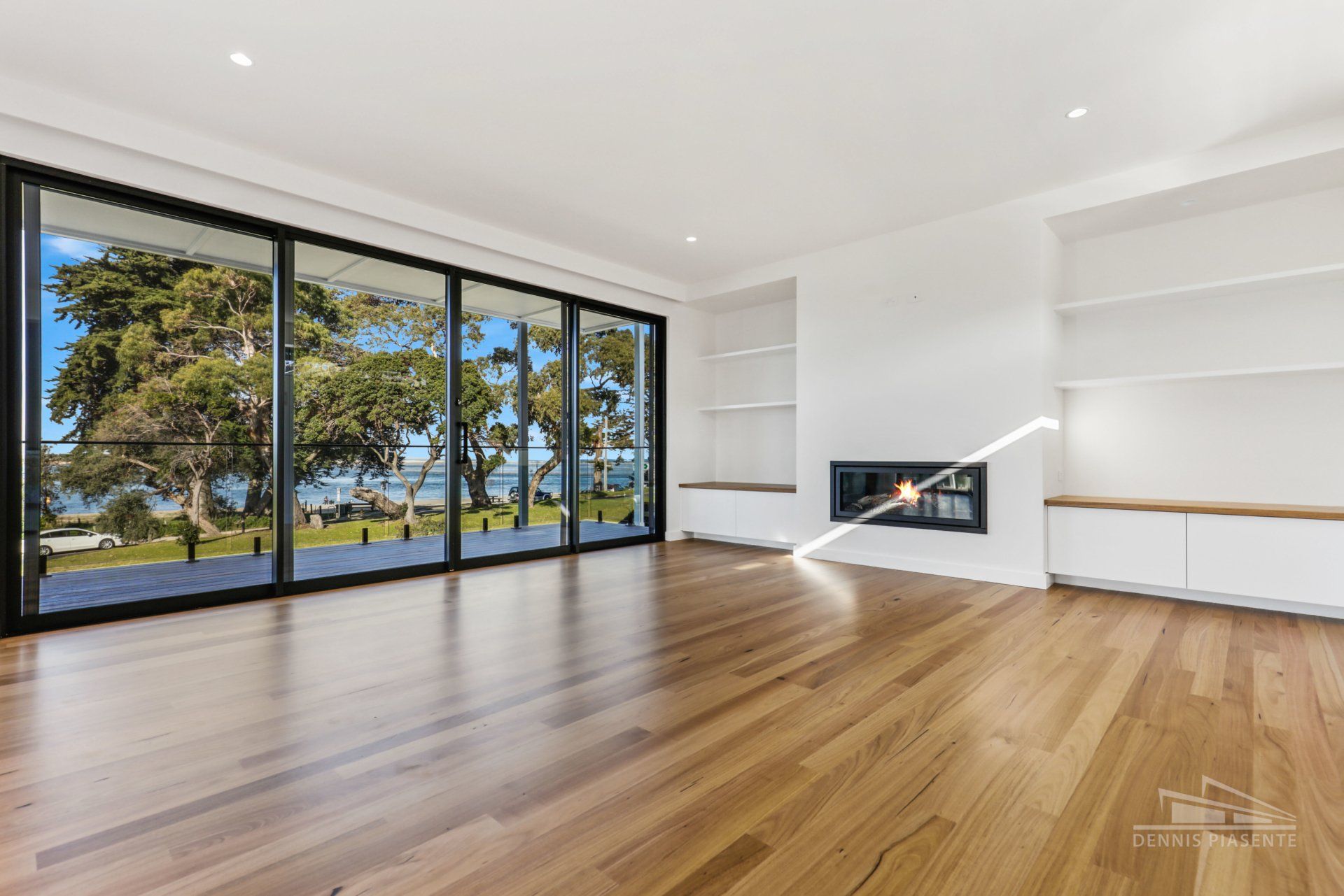 An empty living room with hardwood floors and a fireplace.