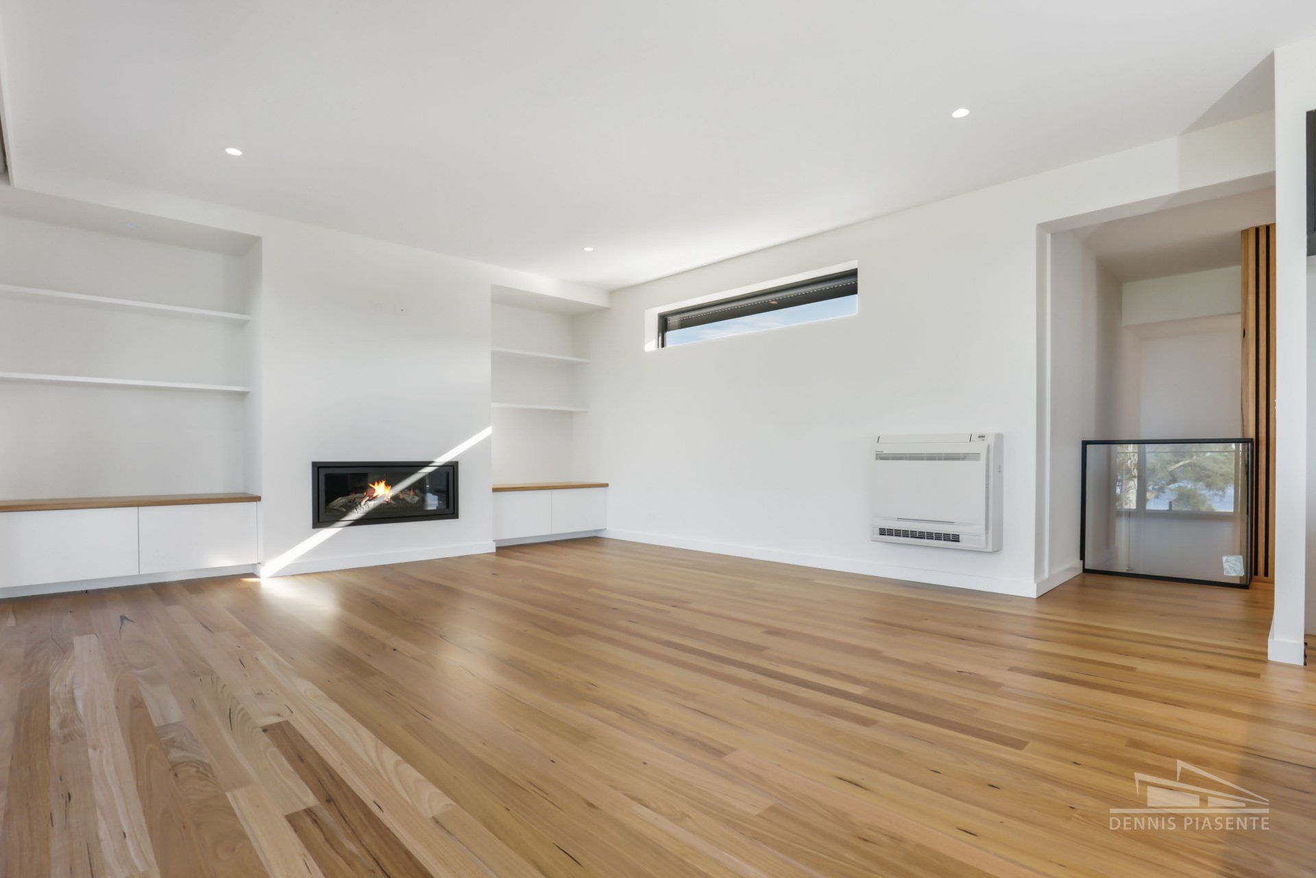 An empty living room with hardwood floors and white walls.