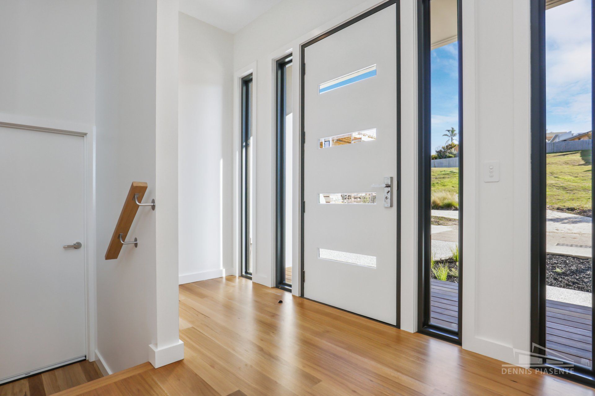 A hallway with a white door and wooden floors in a house.