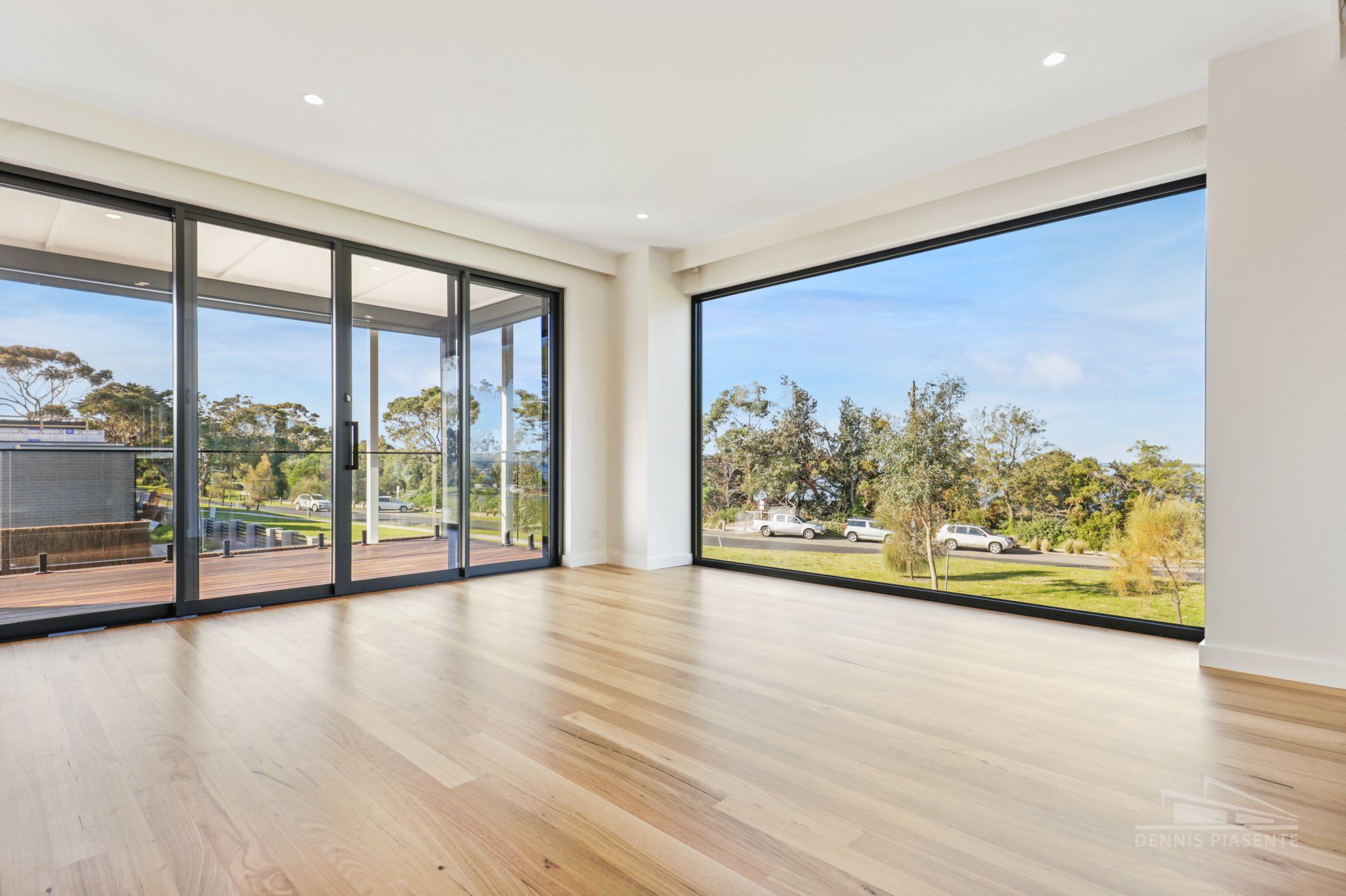An empty living room with a lot of windows and hardwood floors.