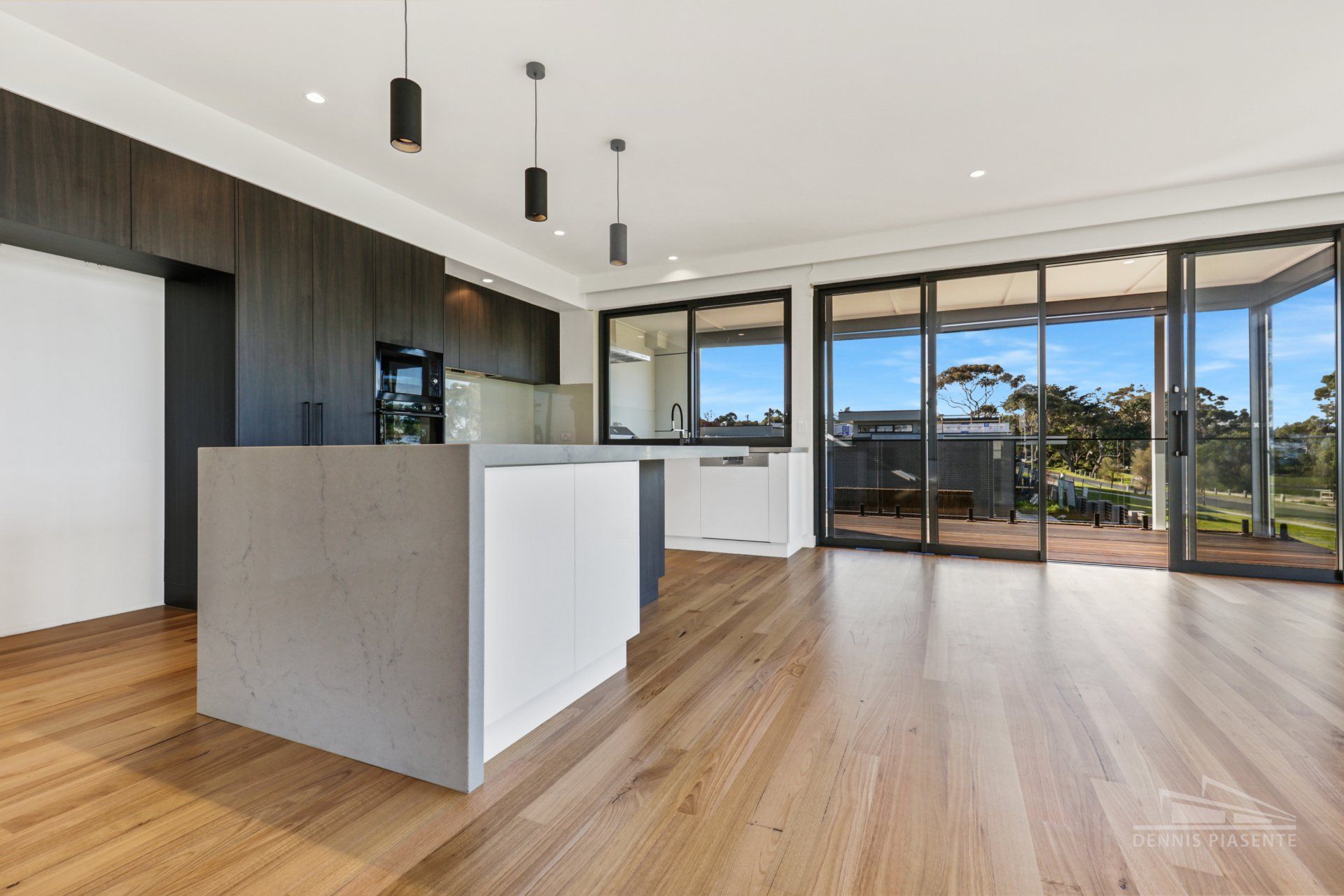 An empty kitchen with a large island and sliding glass doors.