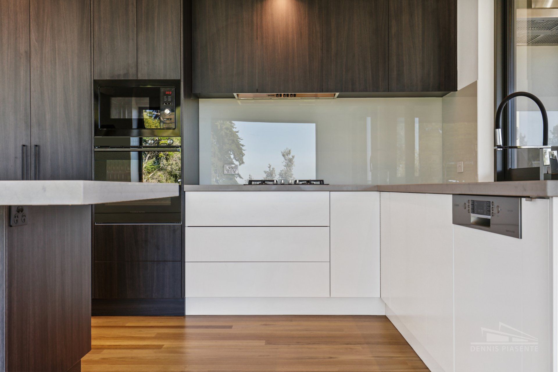 A kitchen with white cabinets and wooden floors and a stove top oven.
