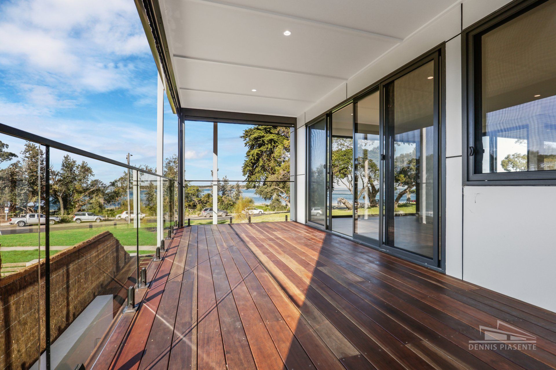 A large wooden deck with a glass railing and sliding glass doors