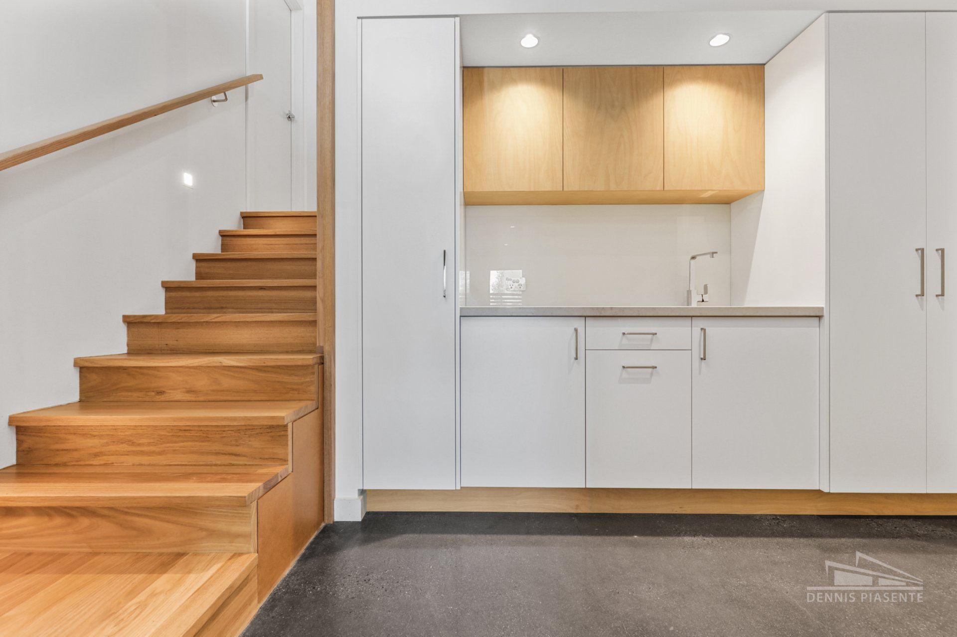 A kitchen with wooden stairs and white cabinets