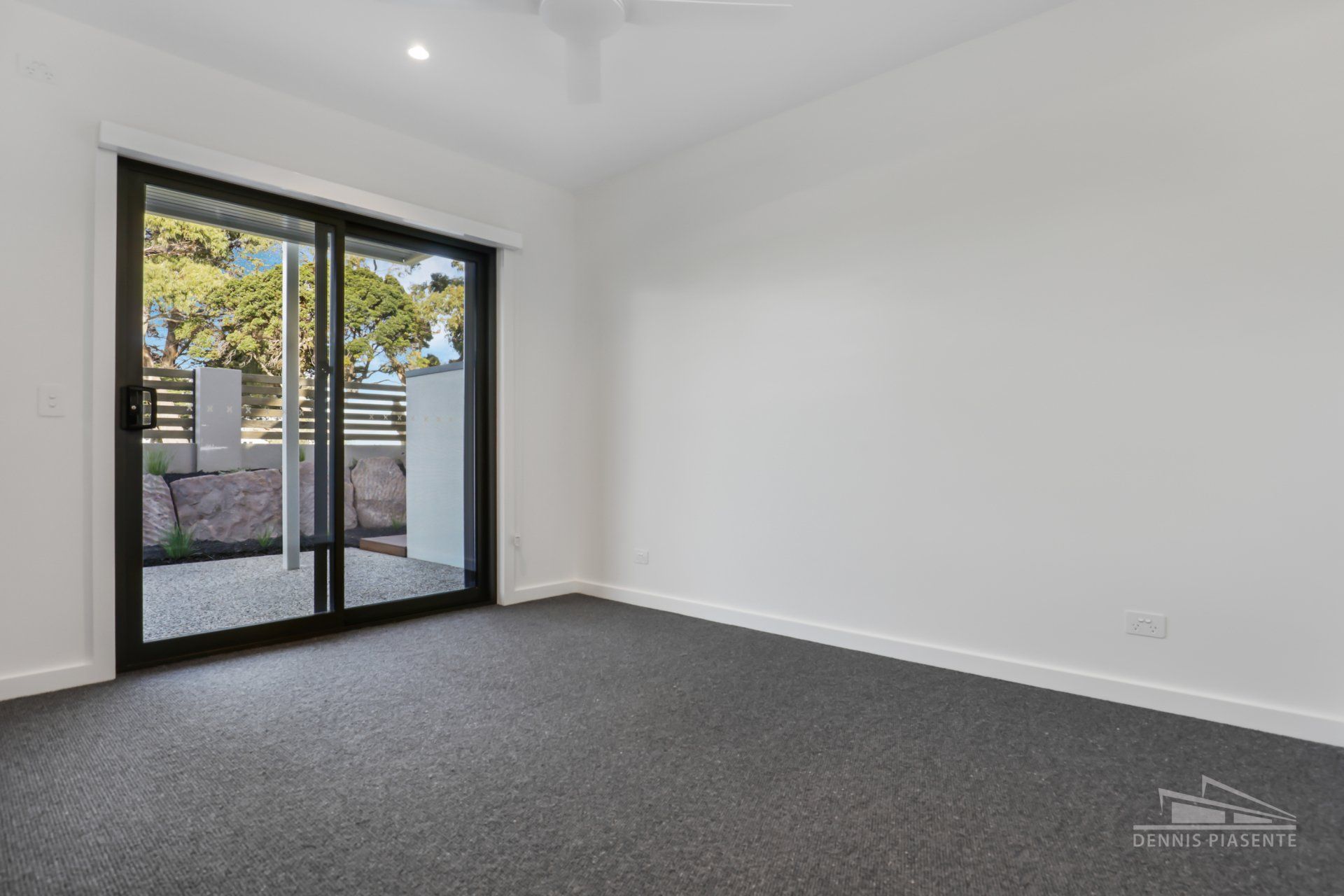 An empty room with a sliding glass door and a balcony.