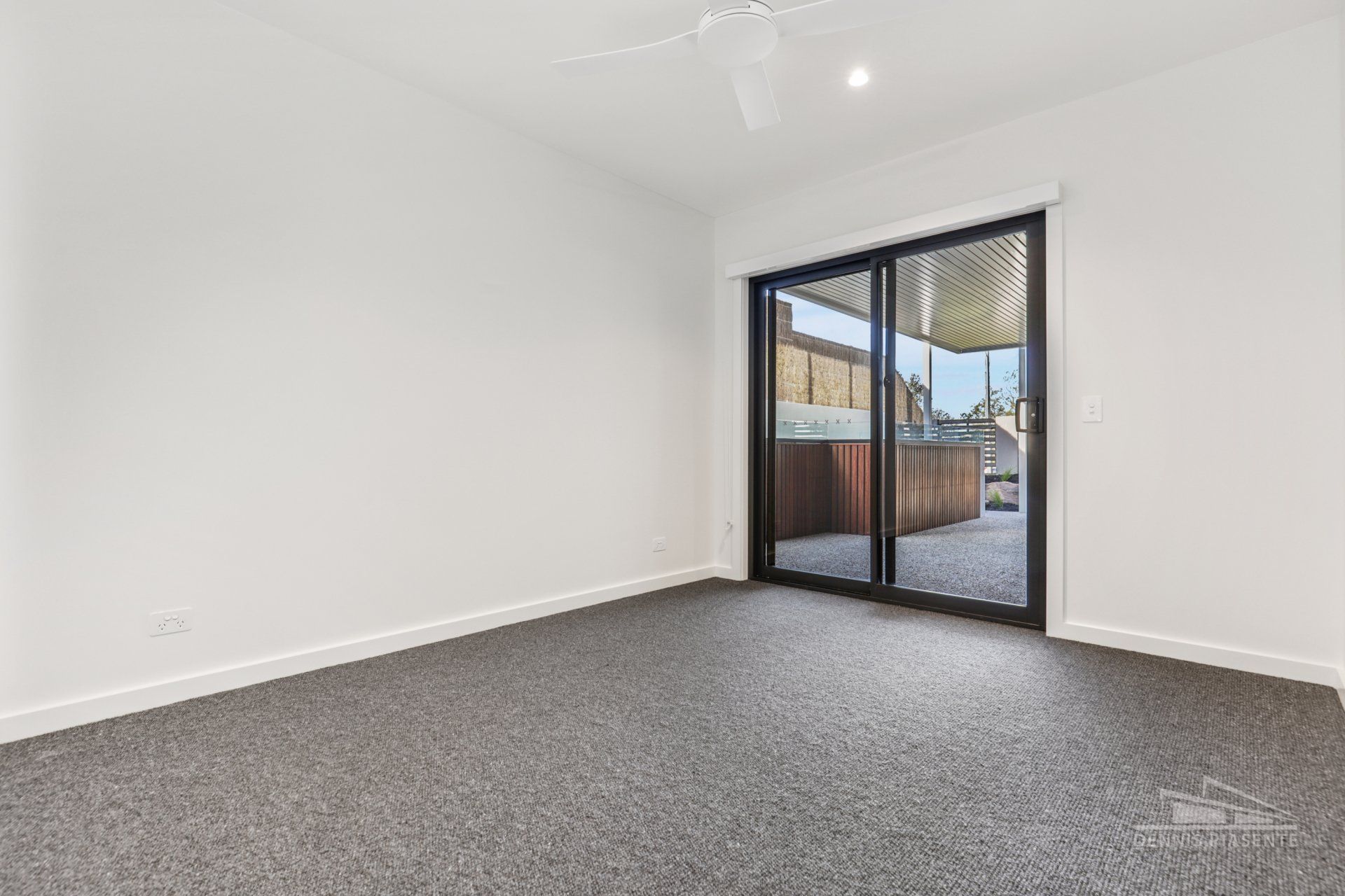 An empty room with a sliding glass door and a ceiling fan.