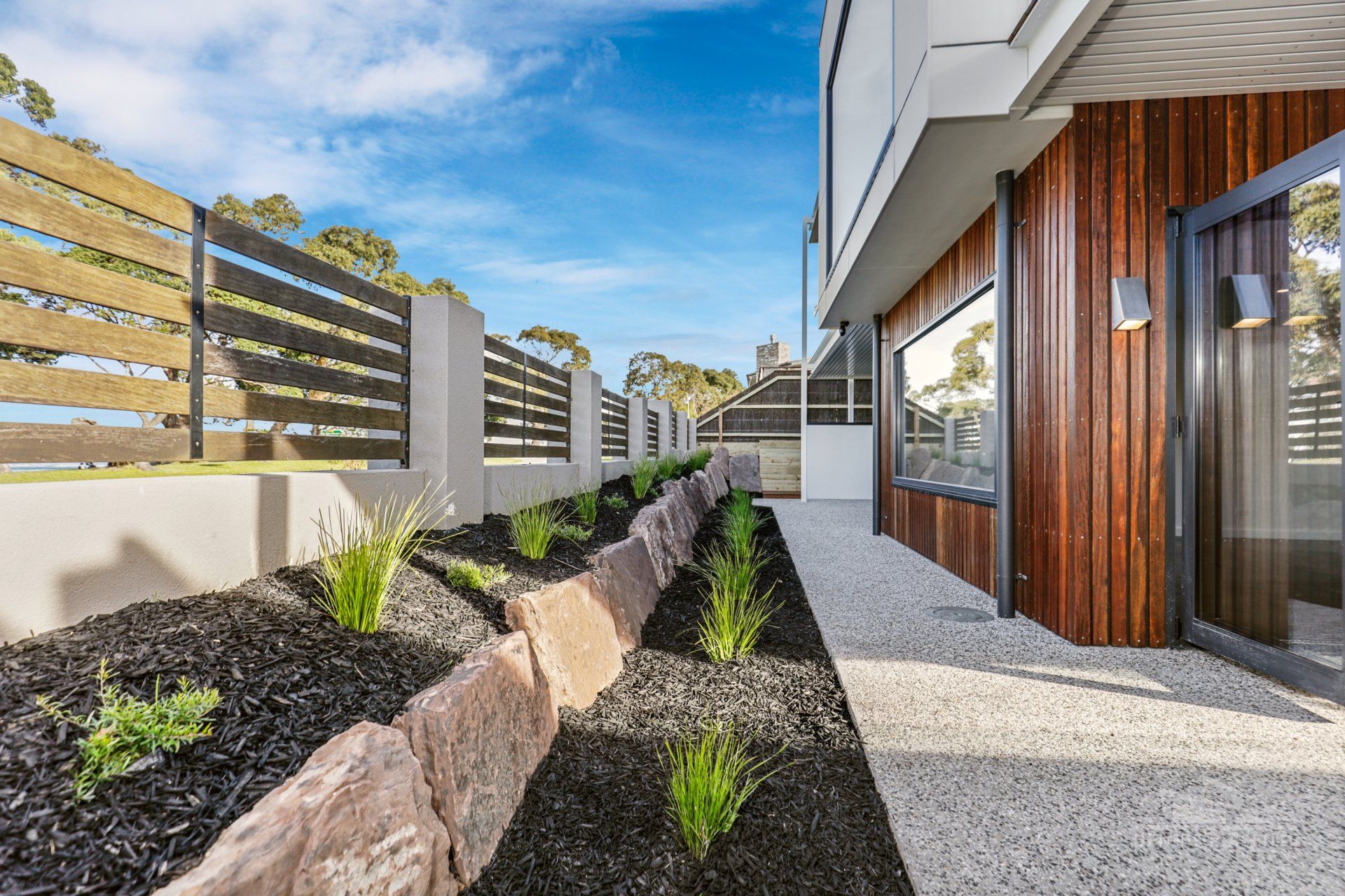 A house with a wooden fence and a garden in front of it.