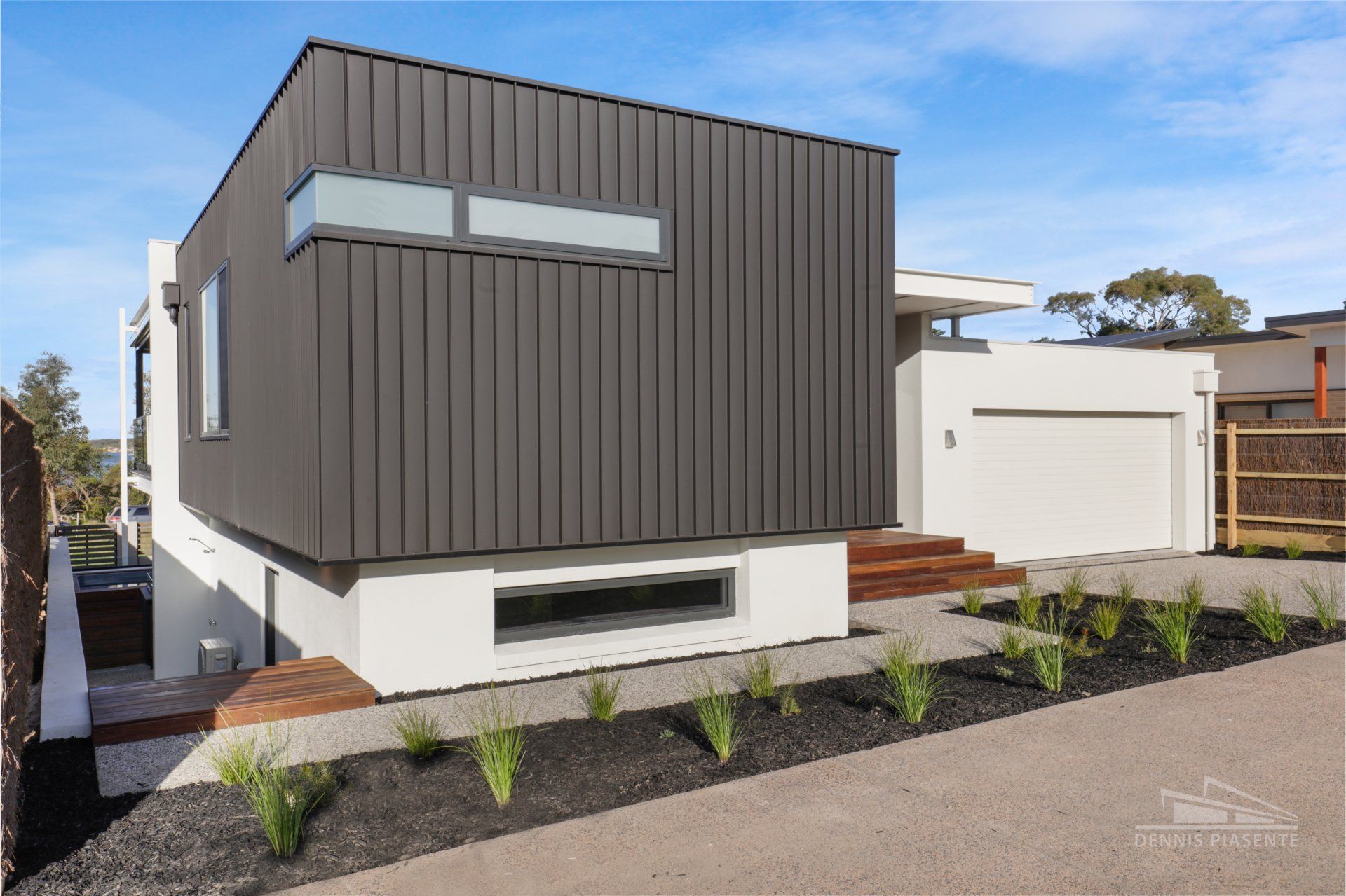A modern house with a gray siding and a white garage