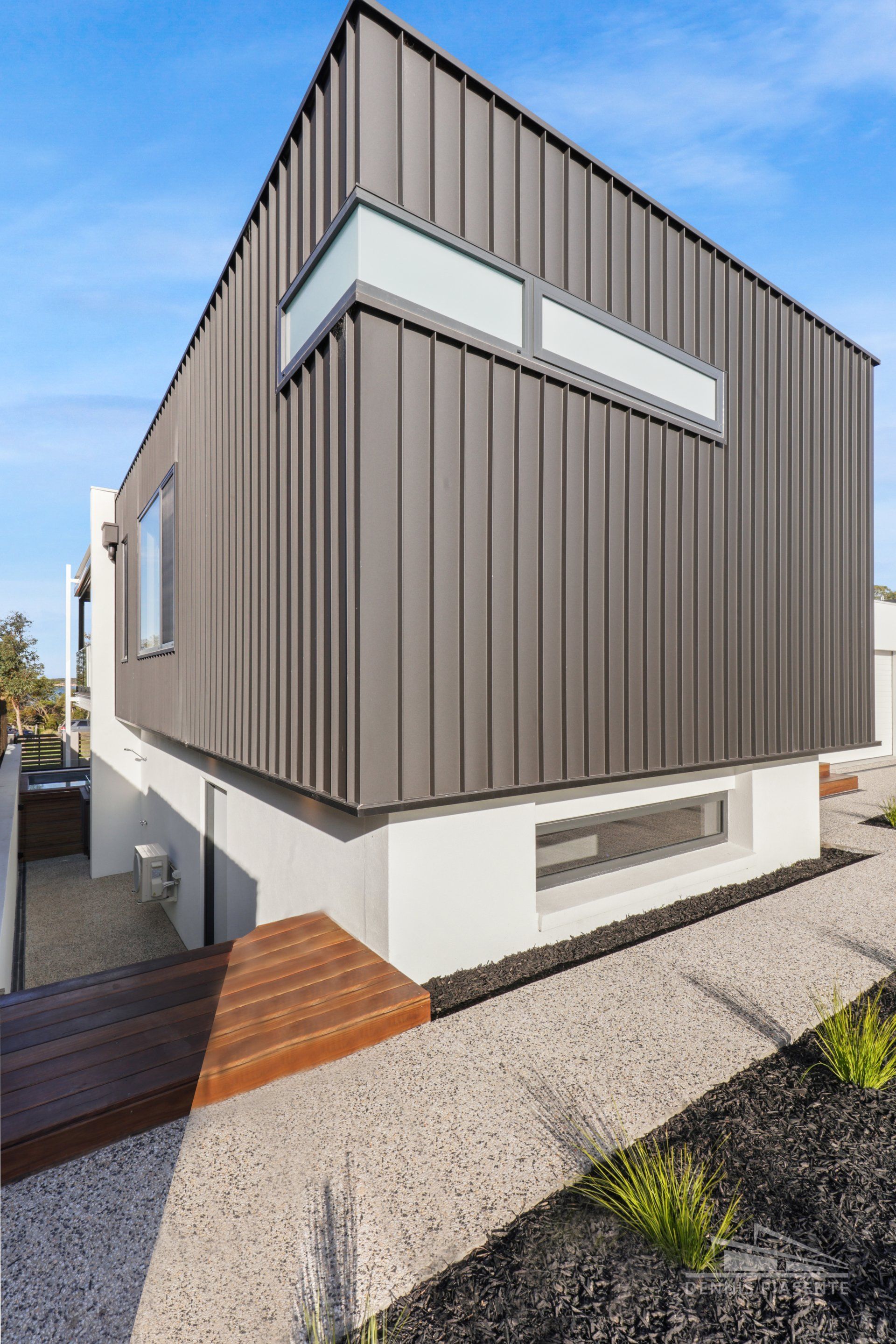 A modern house with a wooden walkway leading to it.