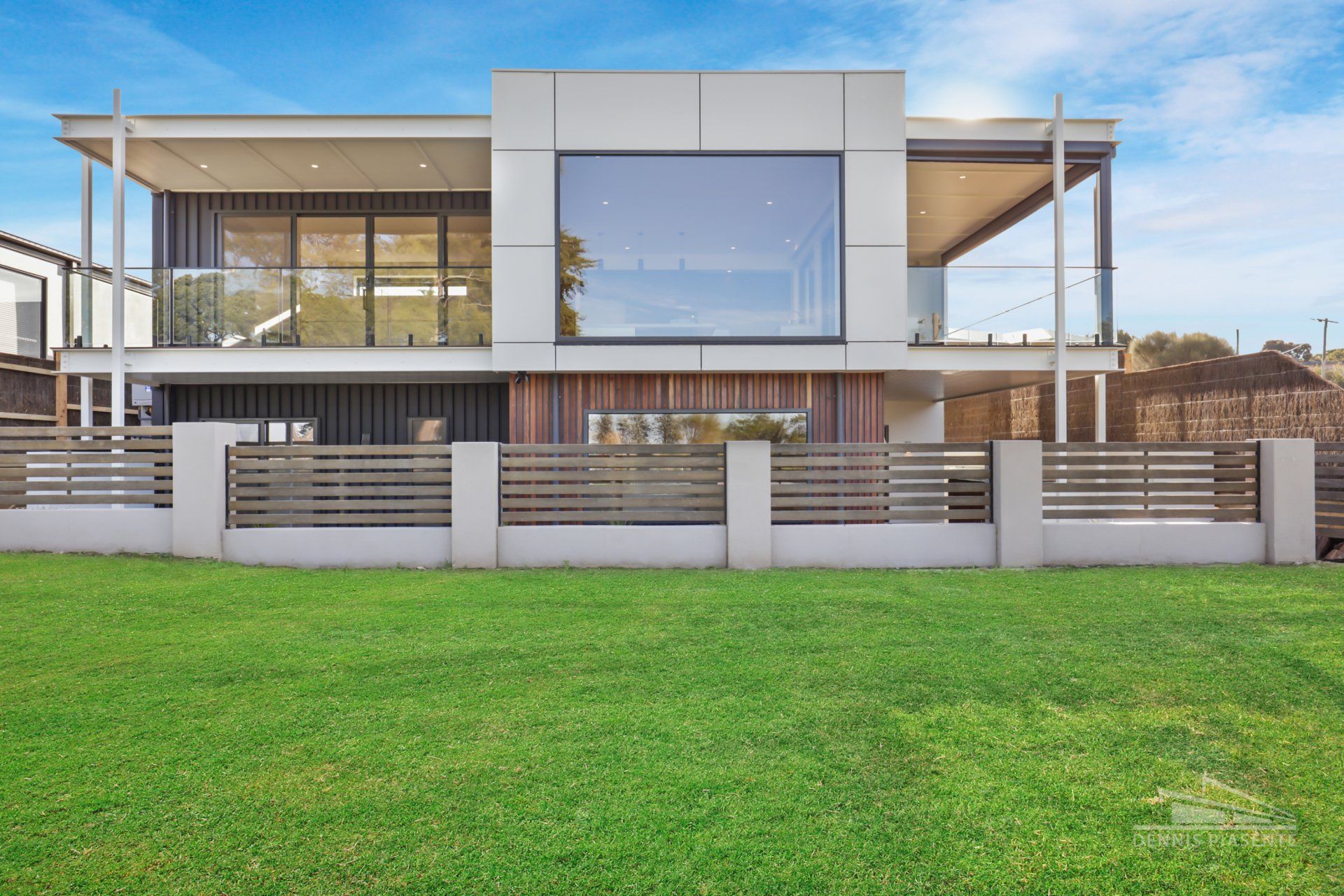 A large house with a fence around it is sitting on top of a lush green field.