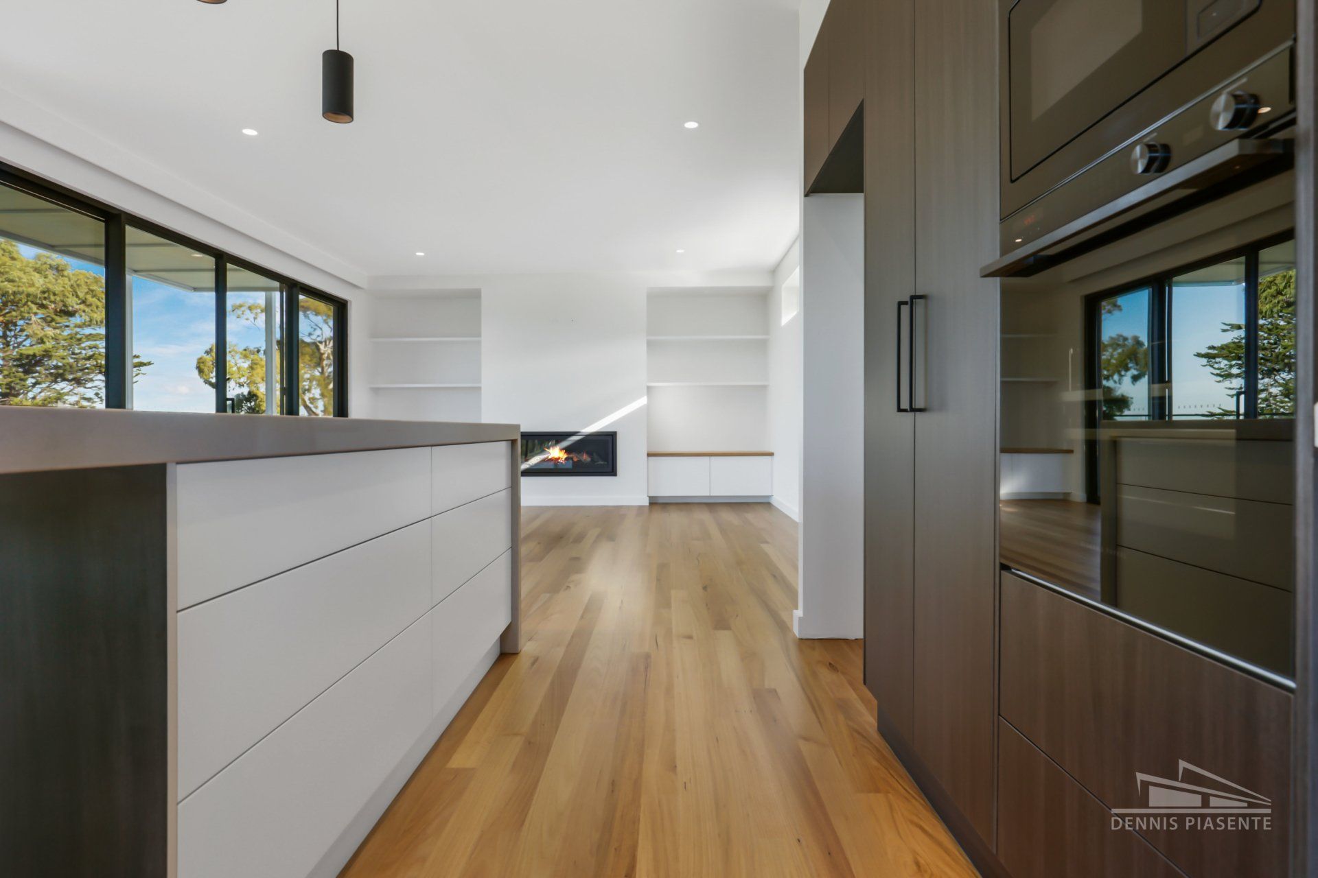 A kitchen with wooden floors , white cabinets , and a black oven.