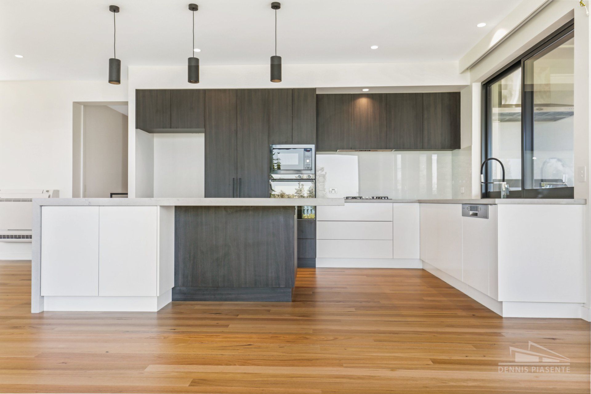 A kitchen with white cabinets and a wooden floor.