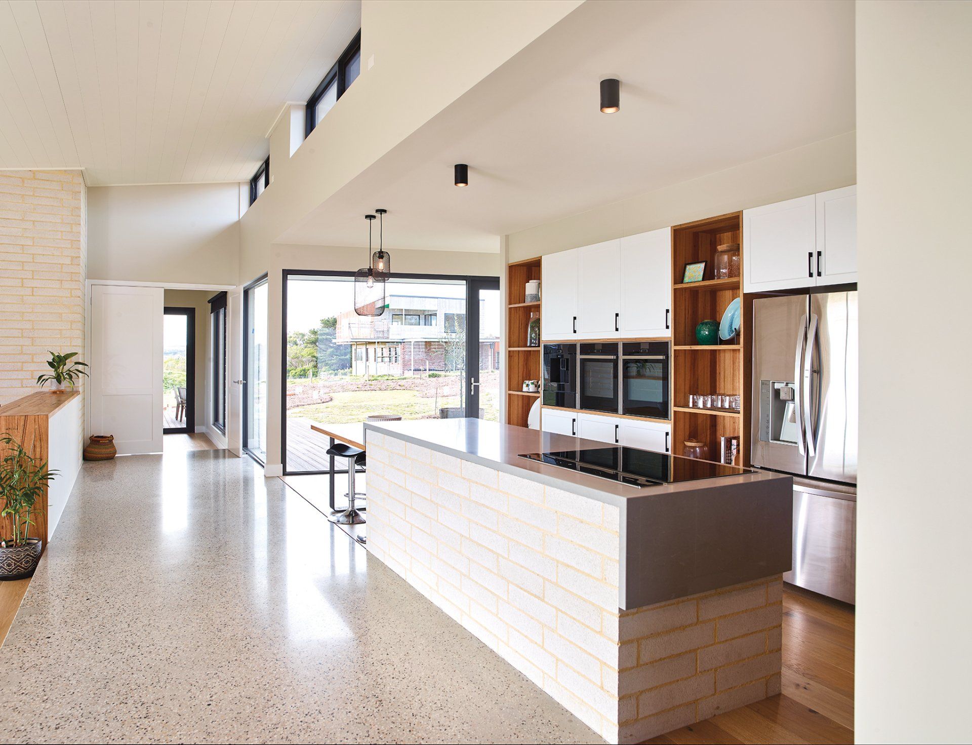 A kitchen with white cabinets , stainless steel appliances , and a large island.