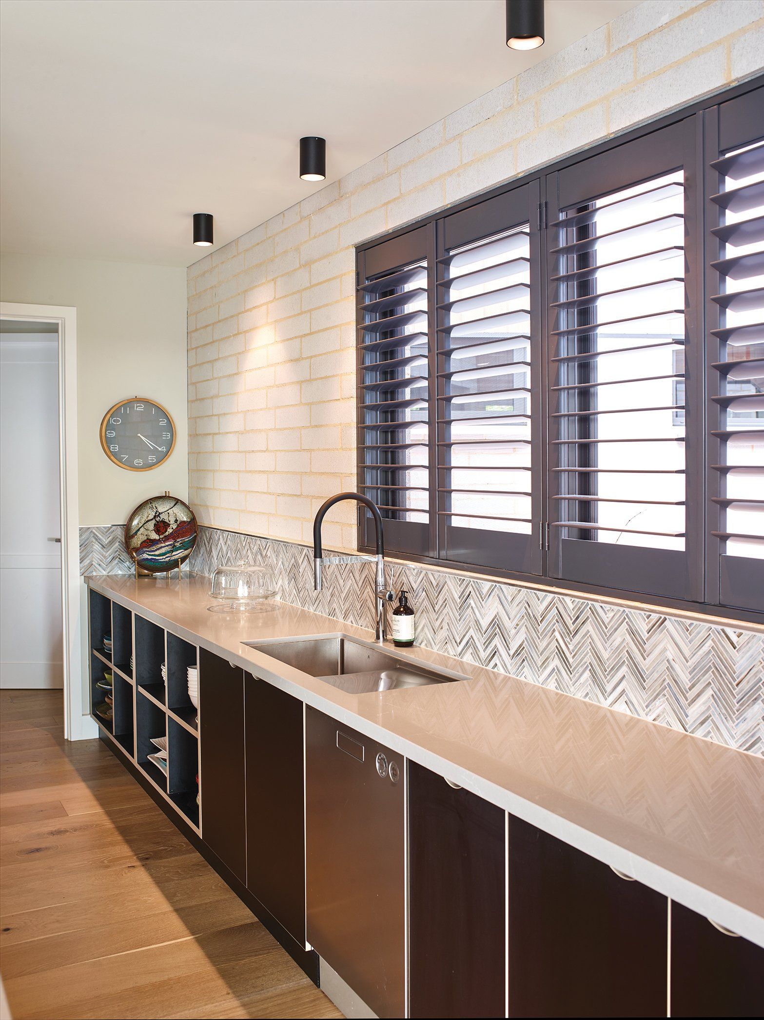 A kitchen with a sink and shutters on the windows