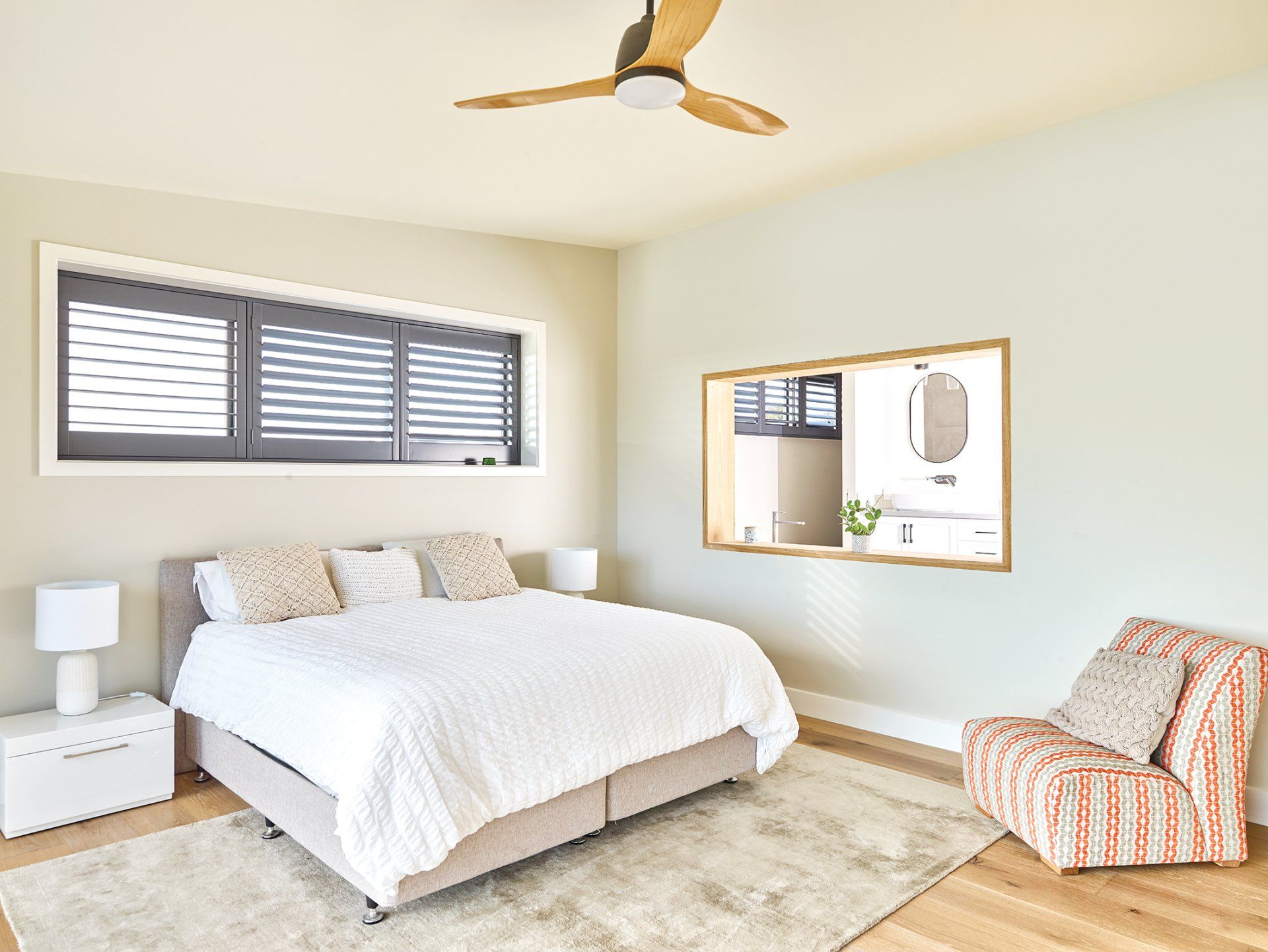 A bedroom with a bed , chair and ceiling fan.