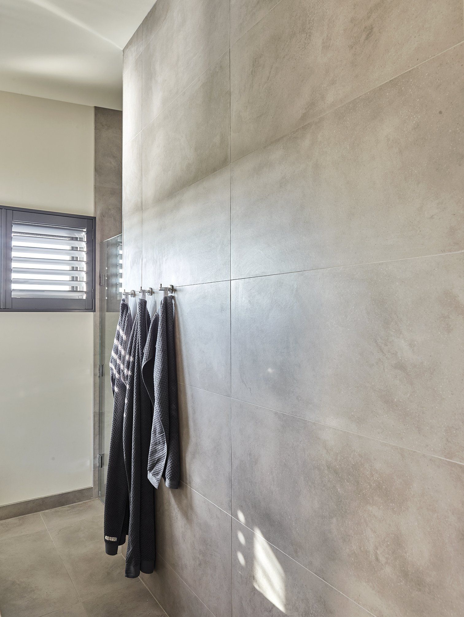 A bathroom with clothes hanging on a wall and a window.