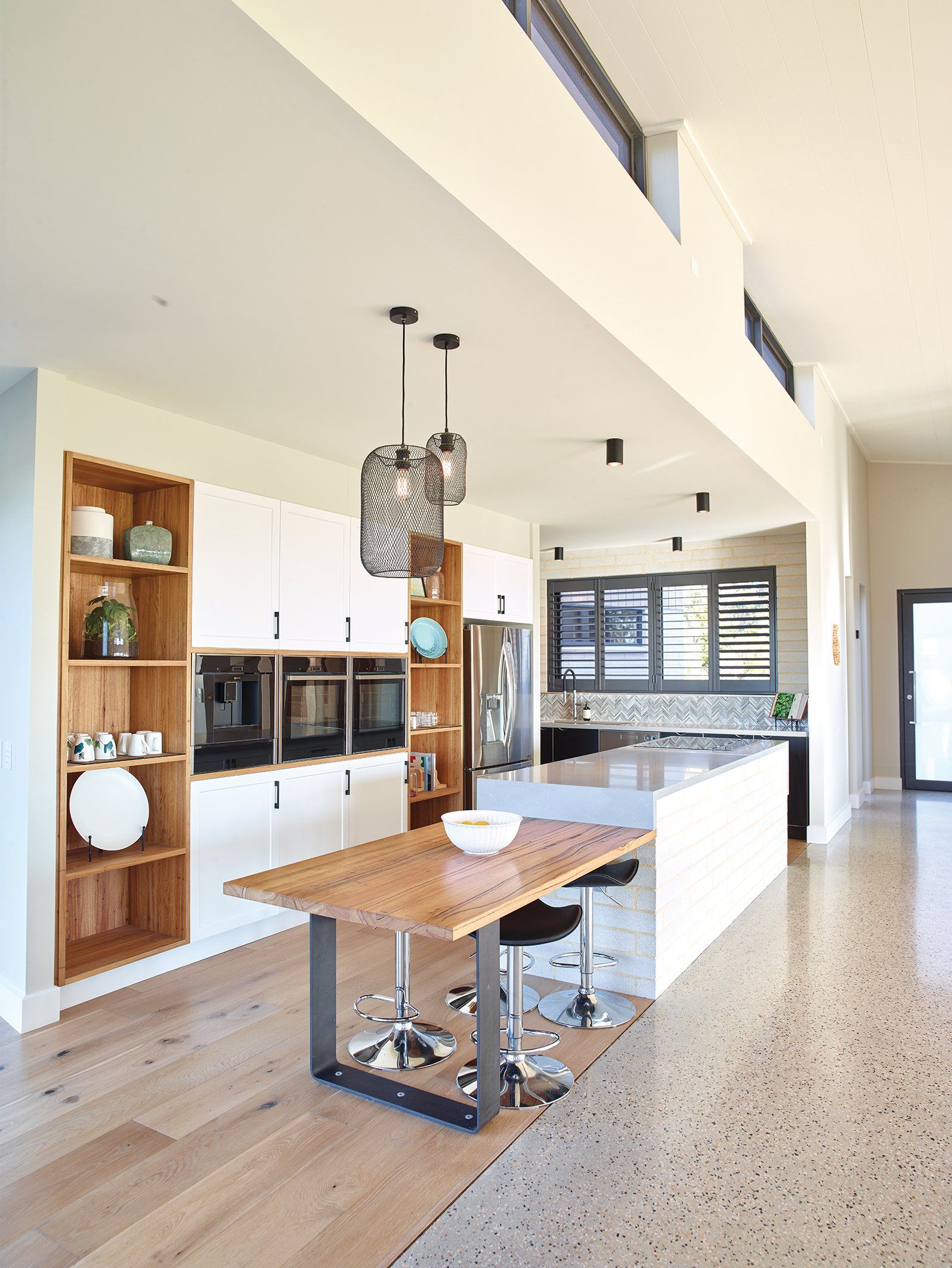 A kitchen with a wooden table and stools in it.
