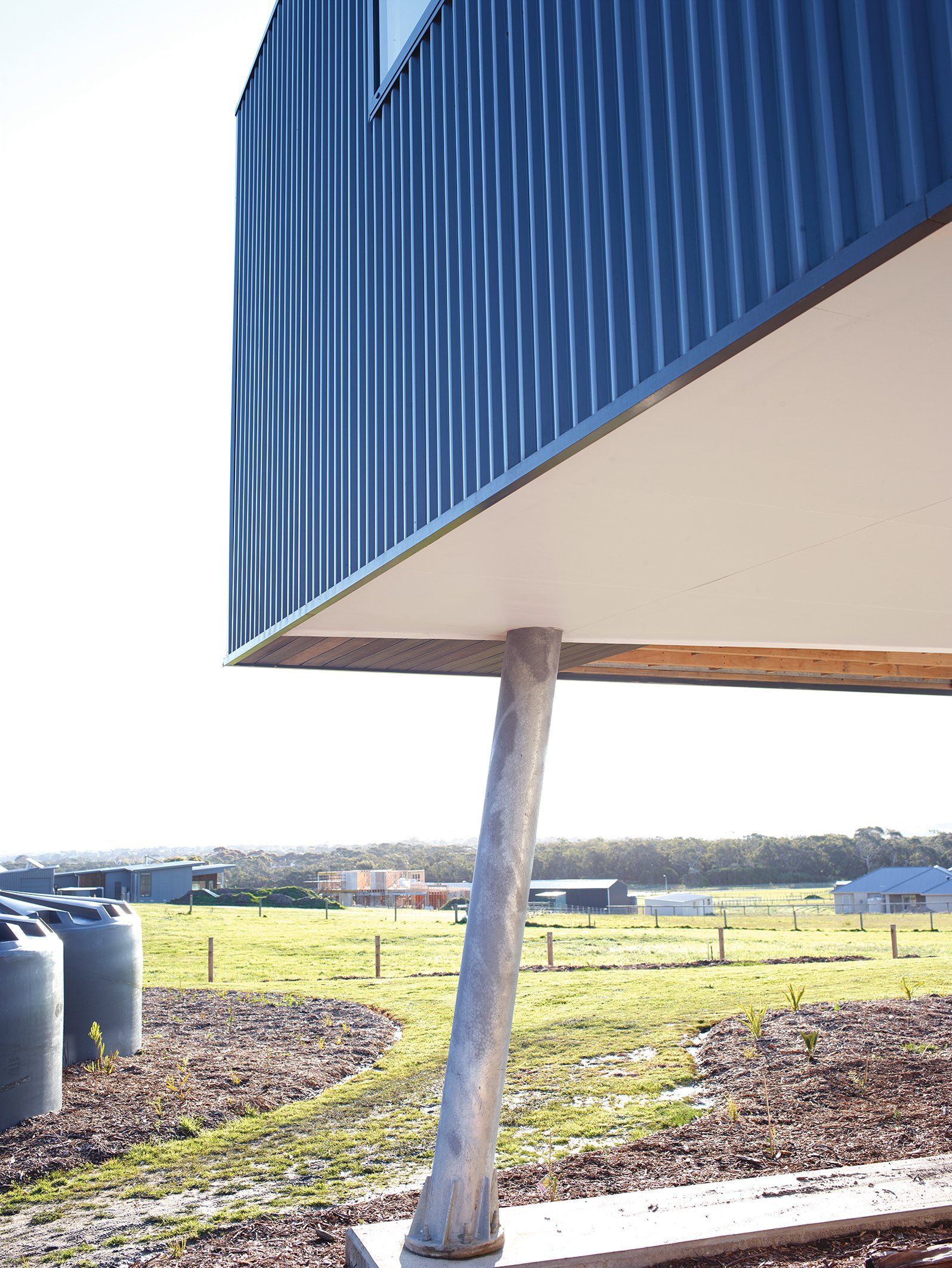 A blue building is sitting on top of a metal pole in a field.