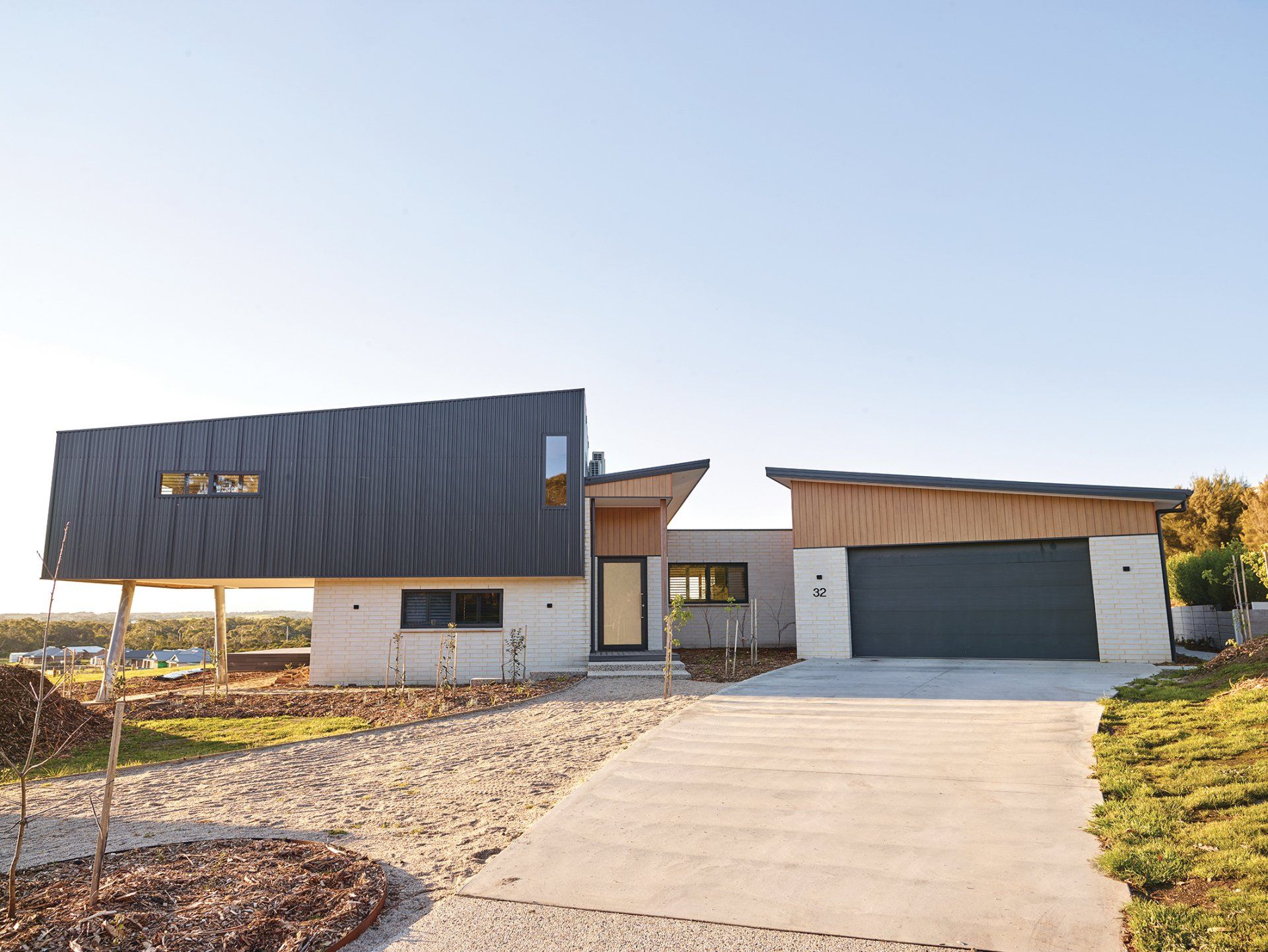 A modern house with a black garage door and a driveway leading to it.