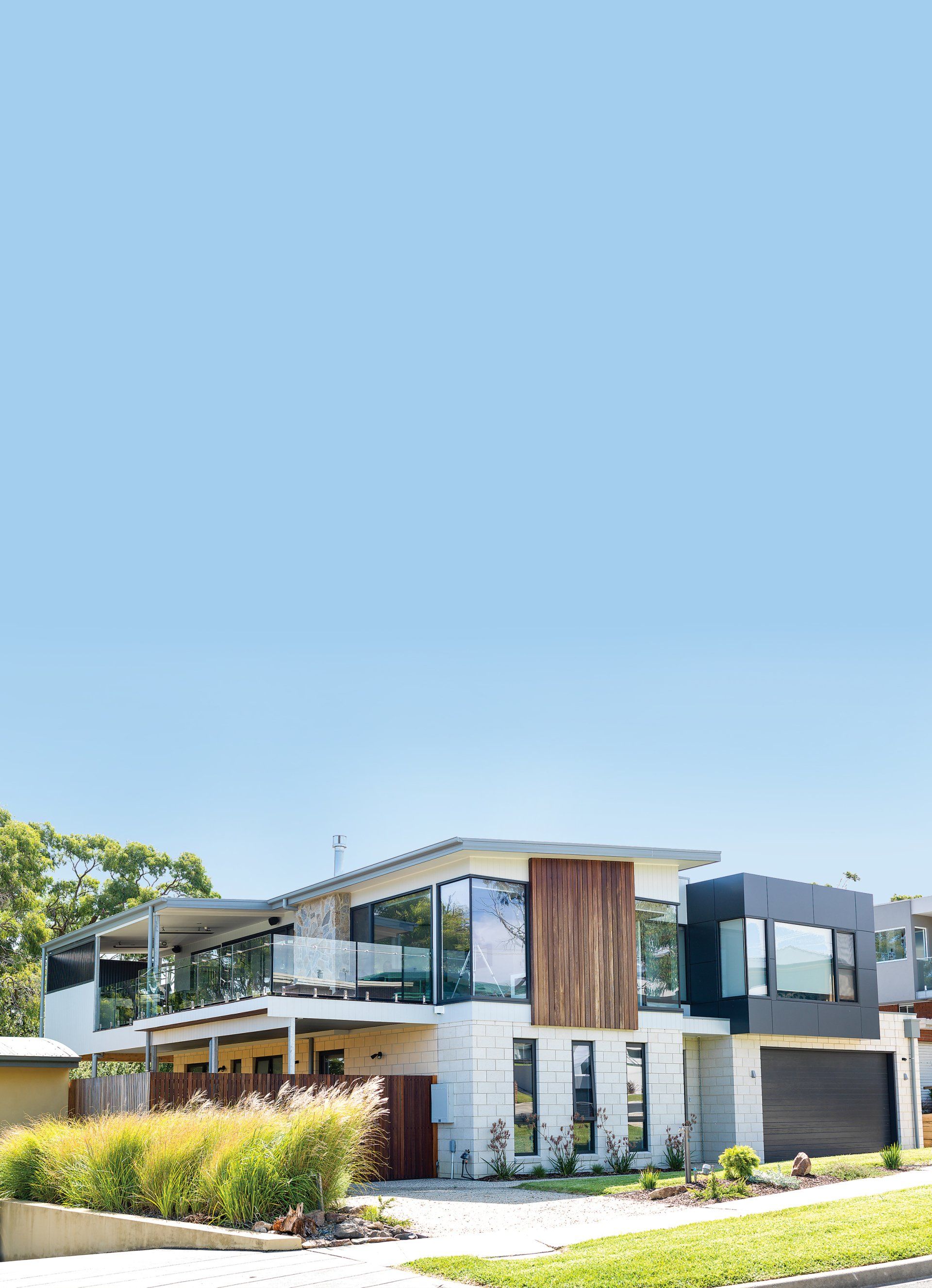 A large modern house with a lot of windows and a blue sky in the background.