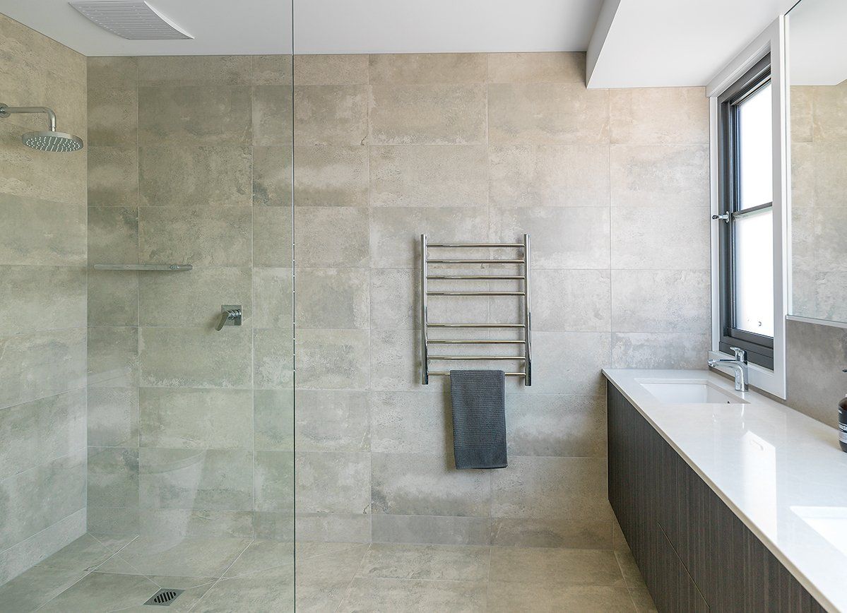 A bathroom with a walk in shower , sink and window.