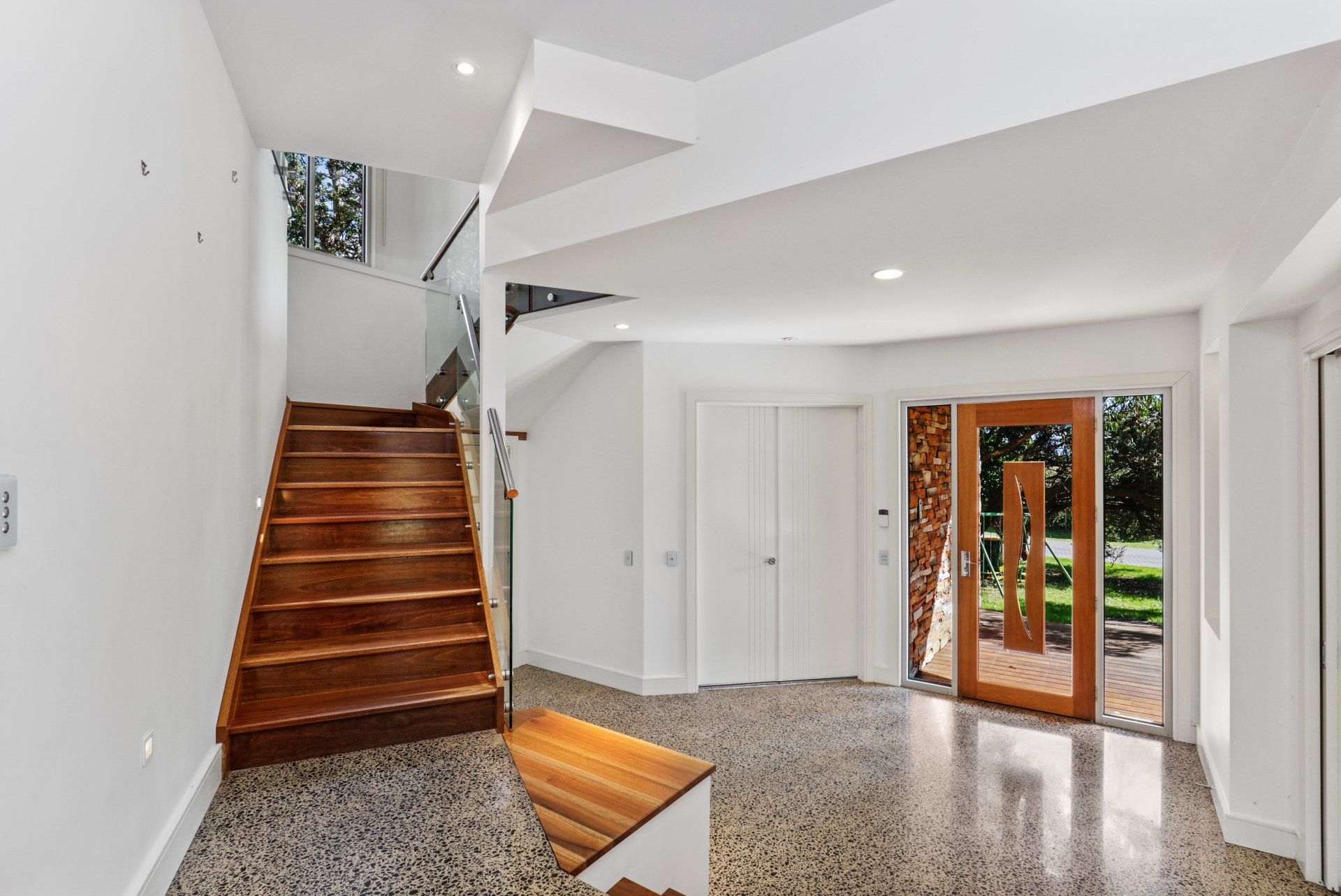 A hallway with stairs and a door in a house.