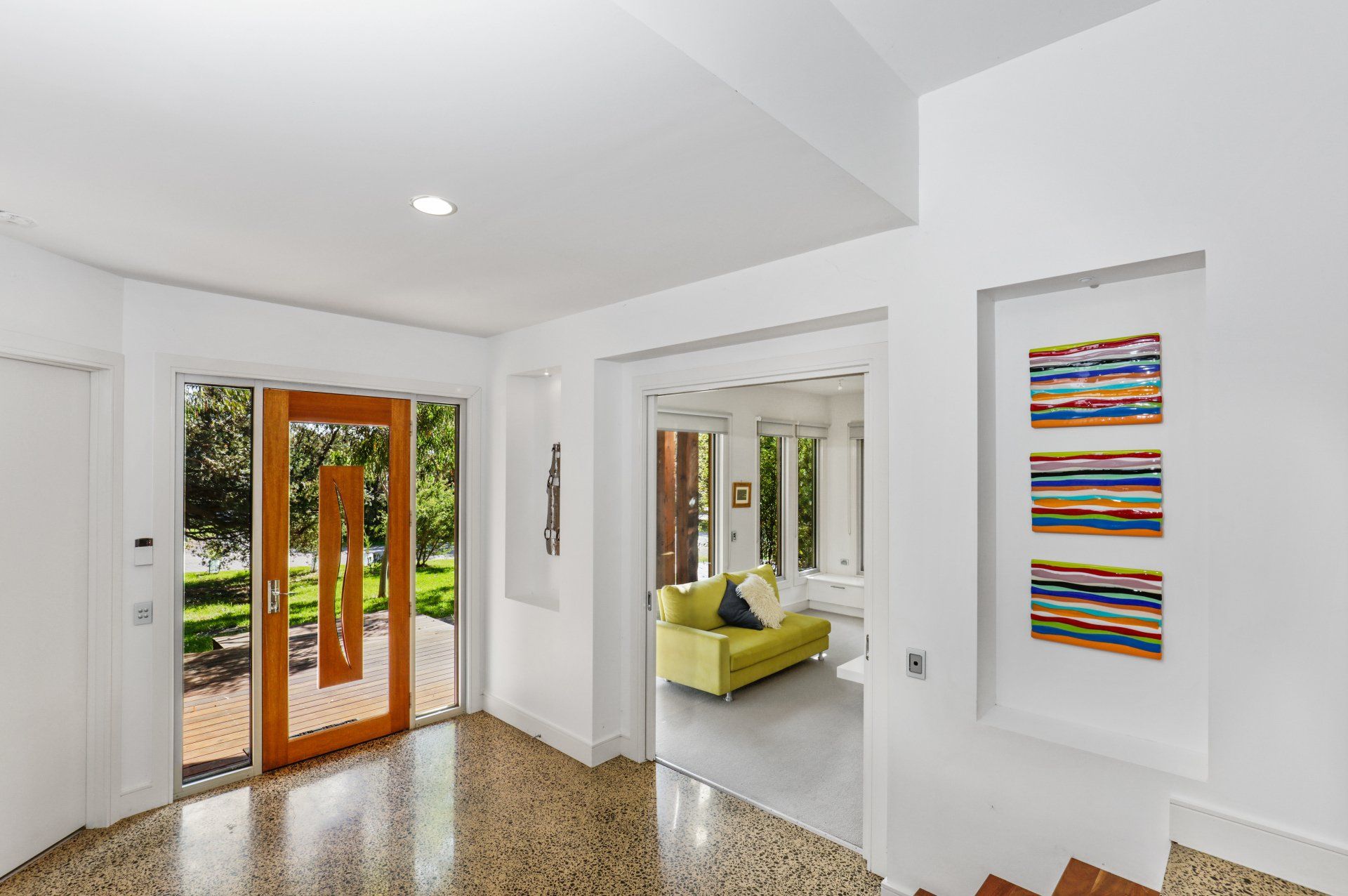 A large hallway with a wooden door and a yellow couch.