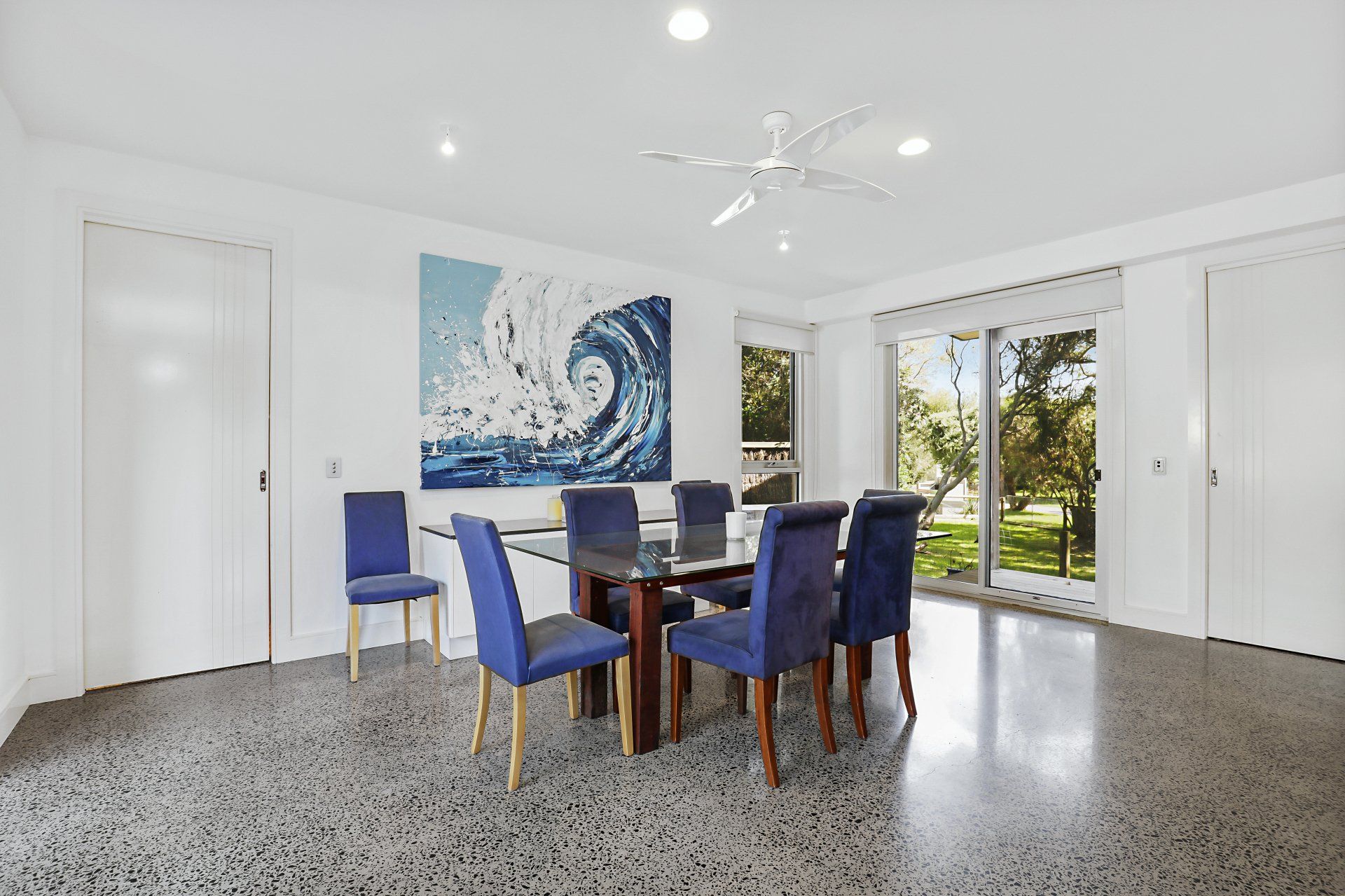 A dining room with a table and chairs and a painting on the wall