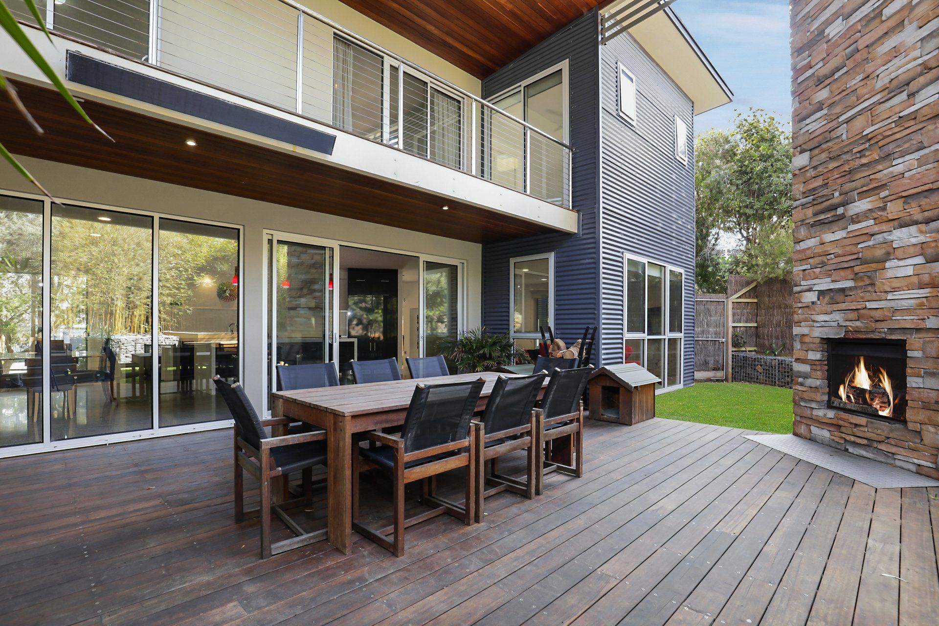 There is a table and chairs on the deck of a house.