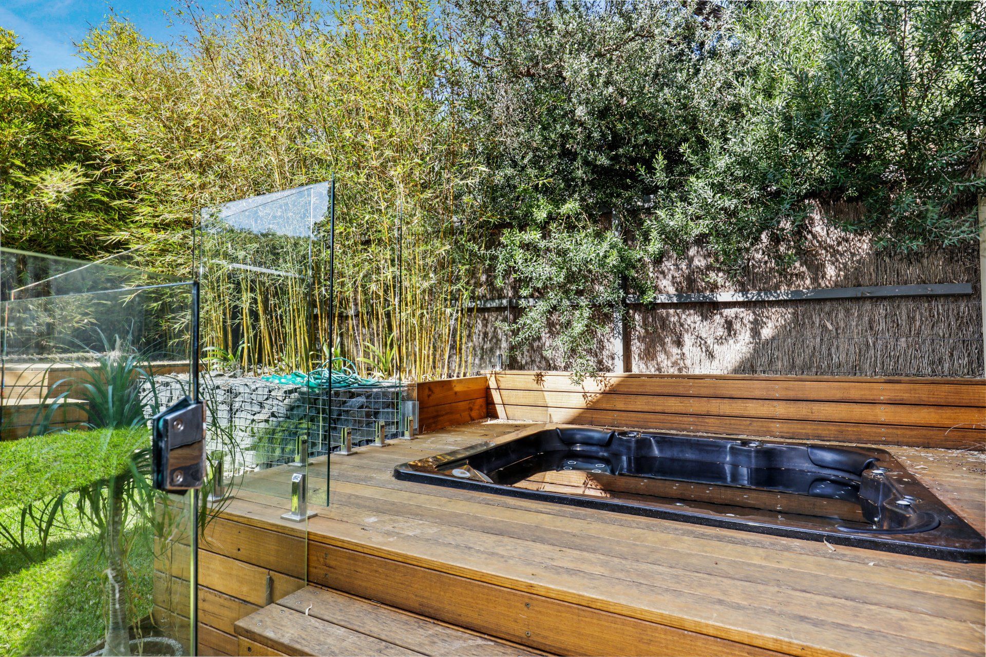 A hot tub is sitting on top of a wooden deck in a backyard.