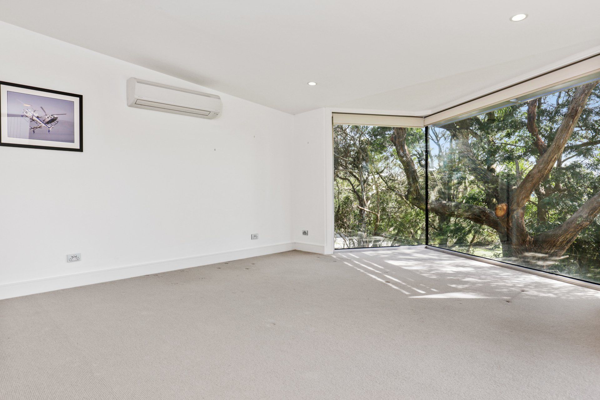 An empty room with a large window and a picture on the wall.