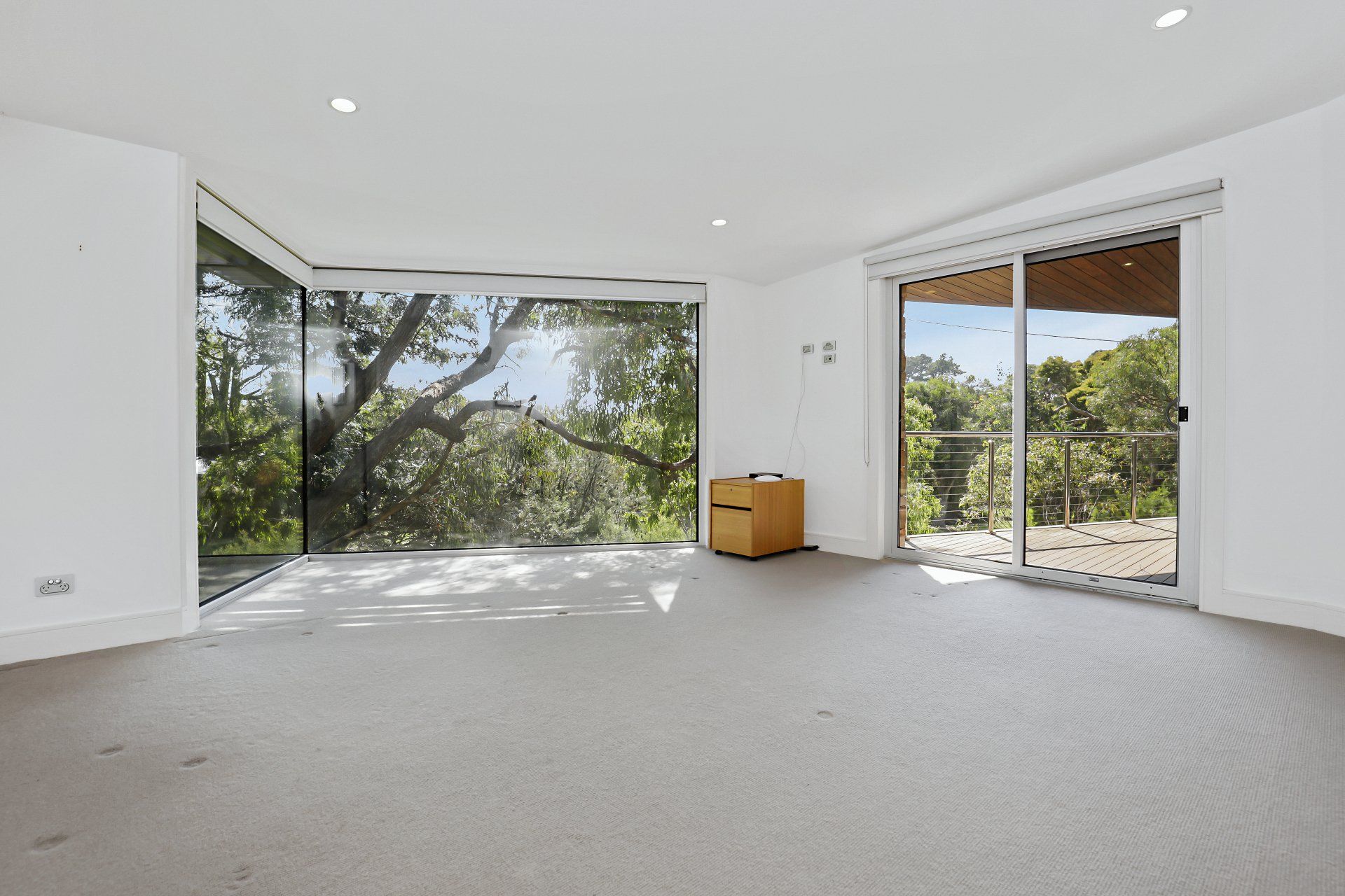 An empty living room with a large window and sliding glass doors.