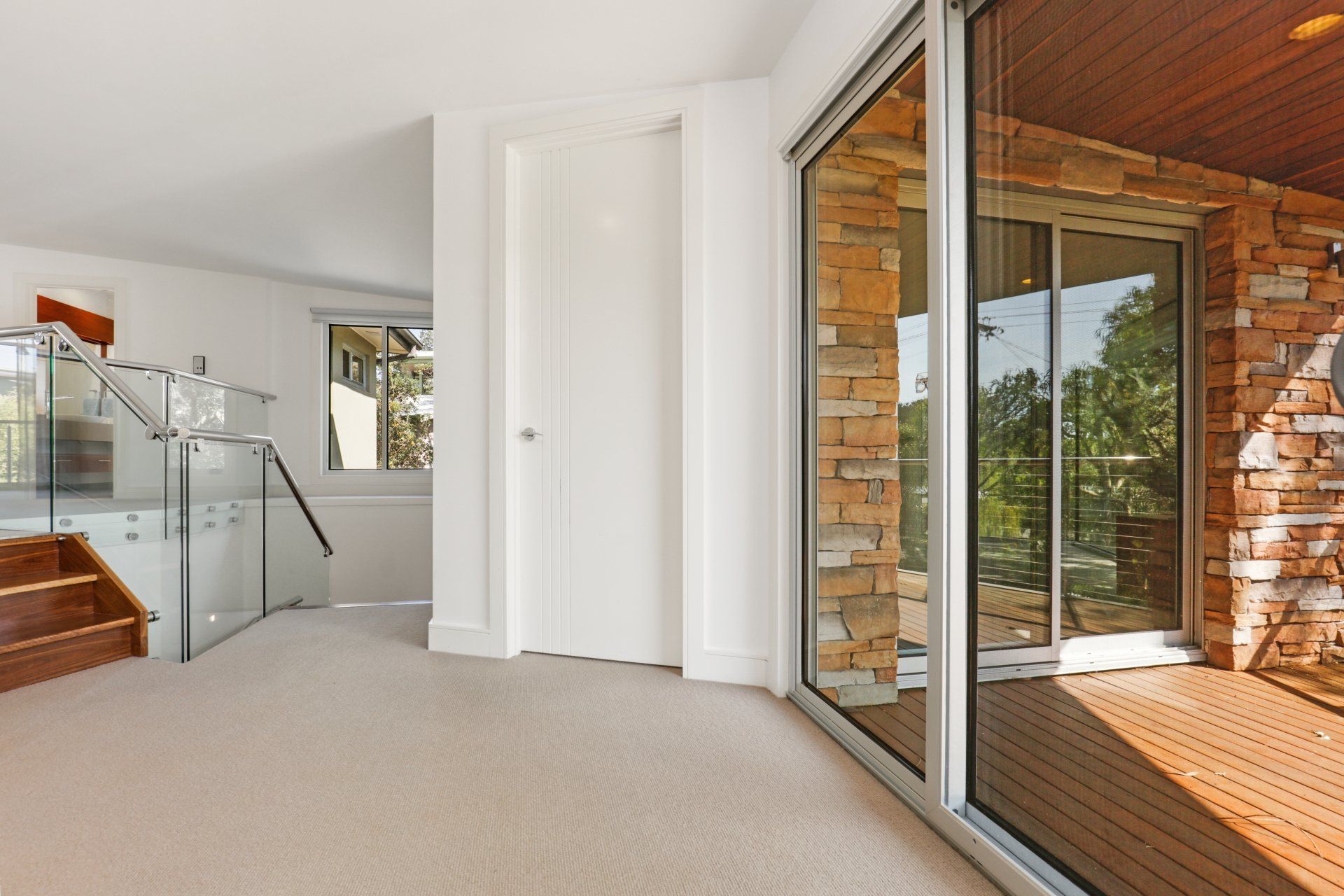 A hallway in a house with a staircase and a sliding glass door.
