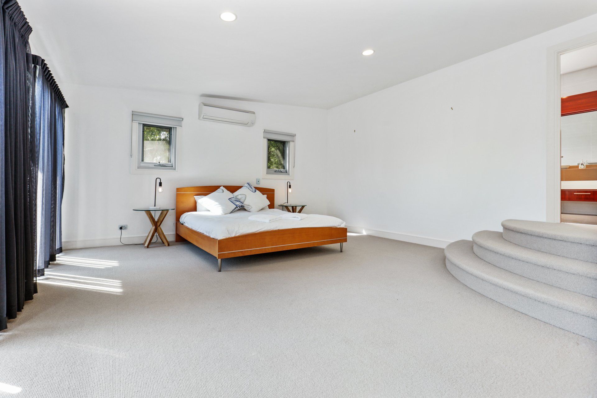 A bedroom with a large bed and stairs leading up to it