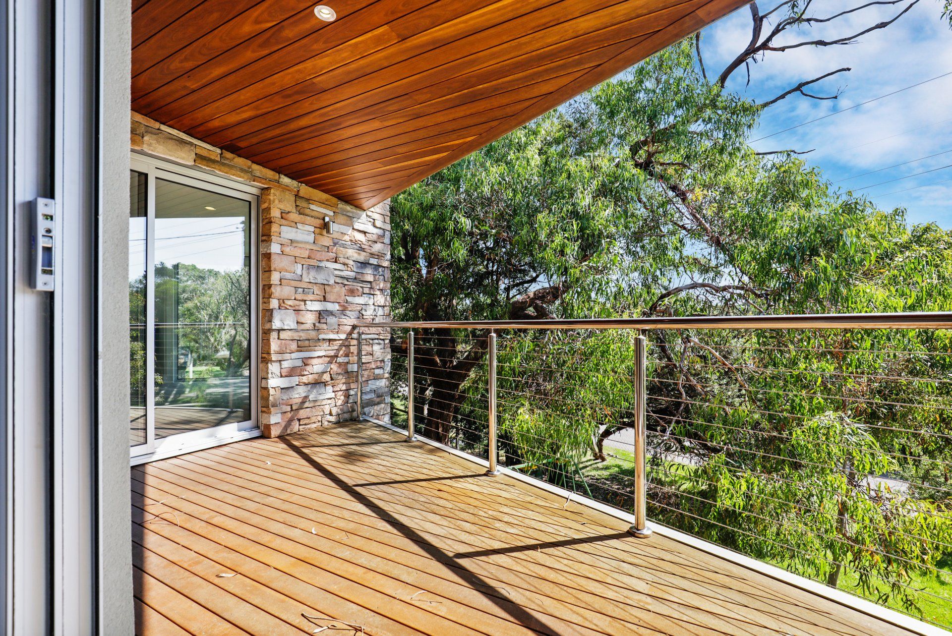 A balcony with a wooden deck and a stainless steel railing