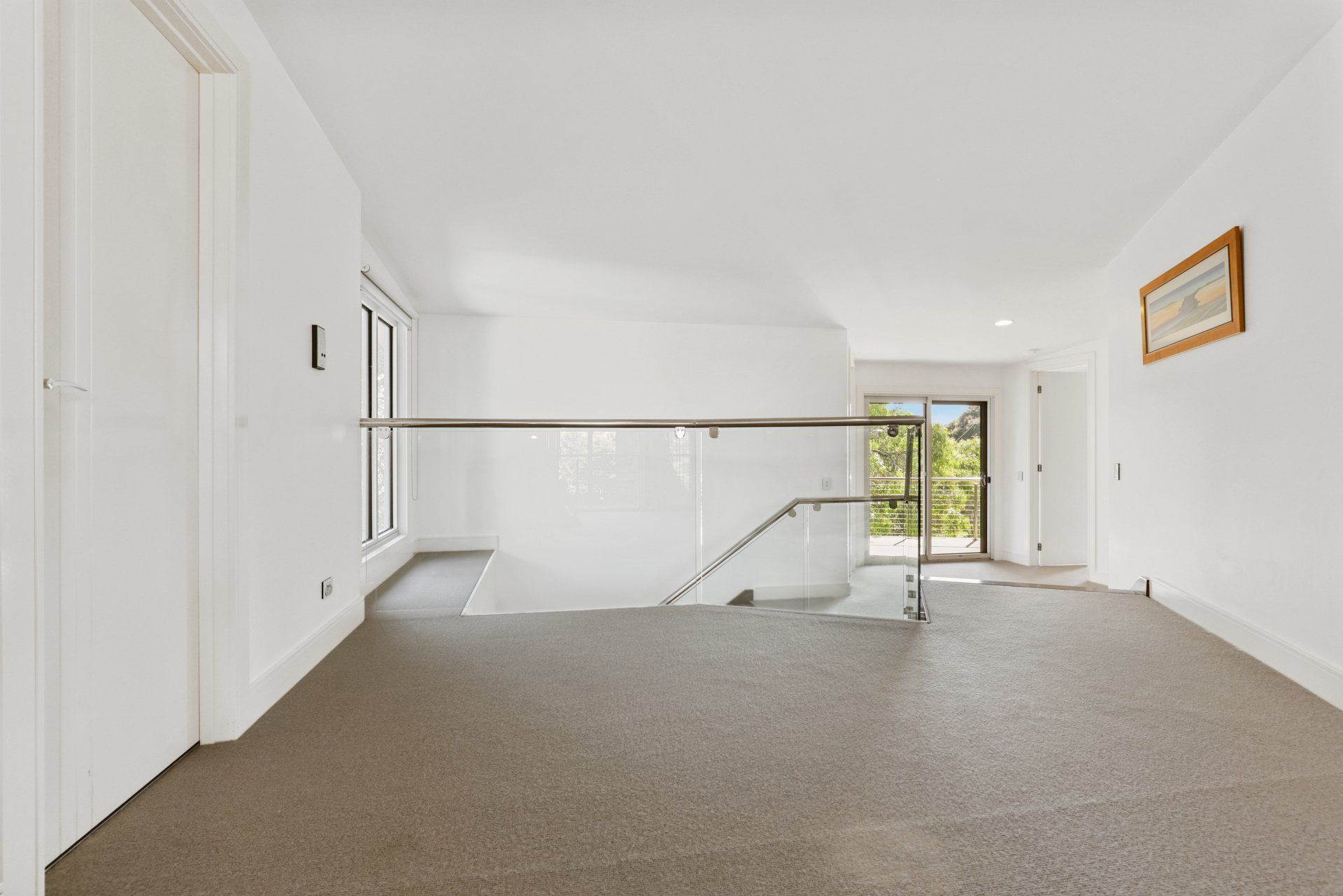 An empty hallway with a staircase and a picture on the wall.