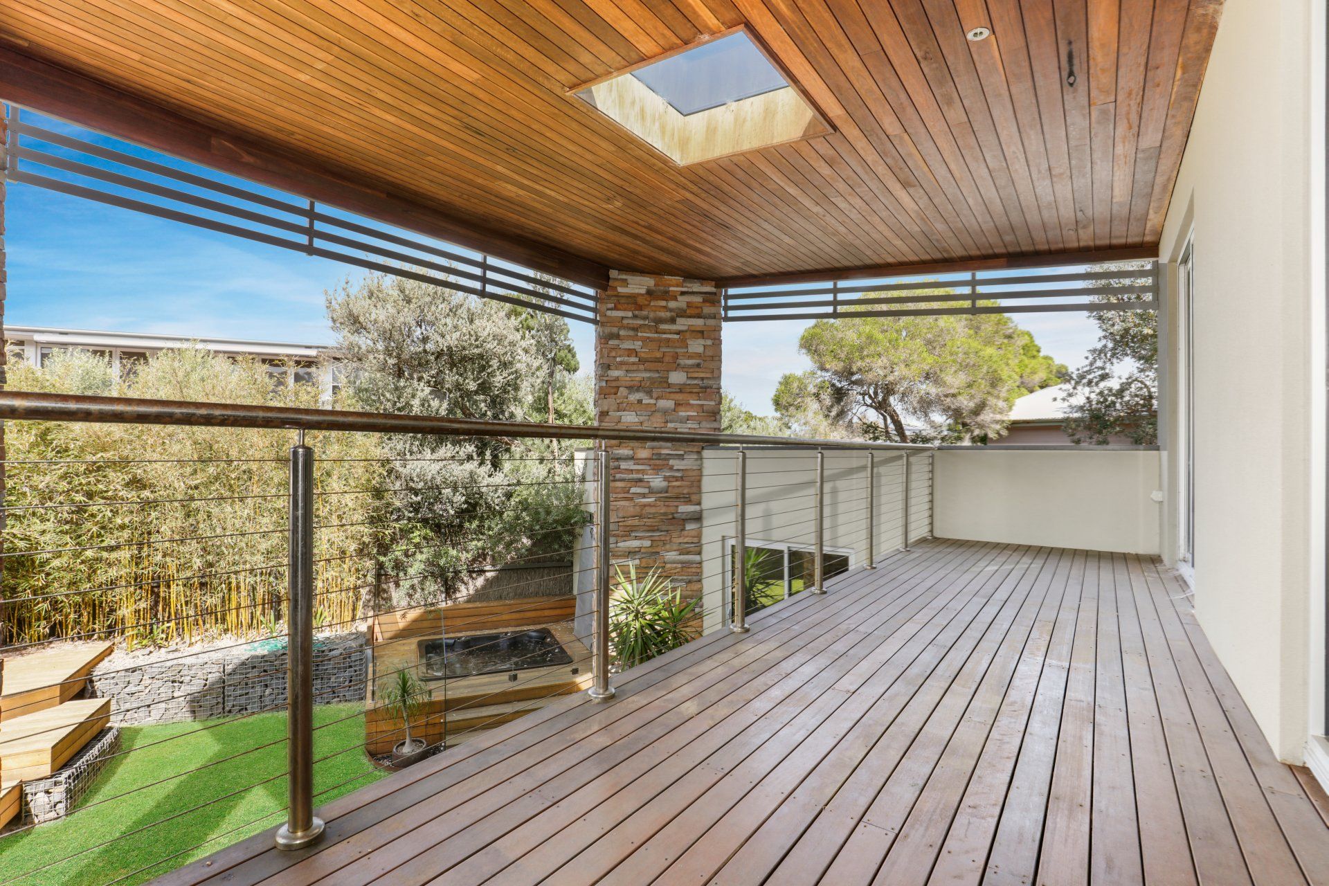 A large wooden deck with a metal railing and a skylight.