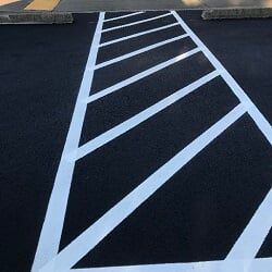 Asphalt parking space with white diagonal lines, for accessible parking.