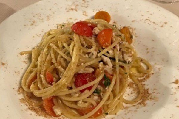 un piatto di spaghetti con pomodorini e pesce