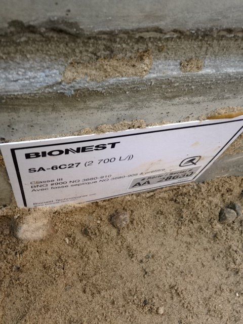 A bionest sign is sitting on top of a pile of sand.