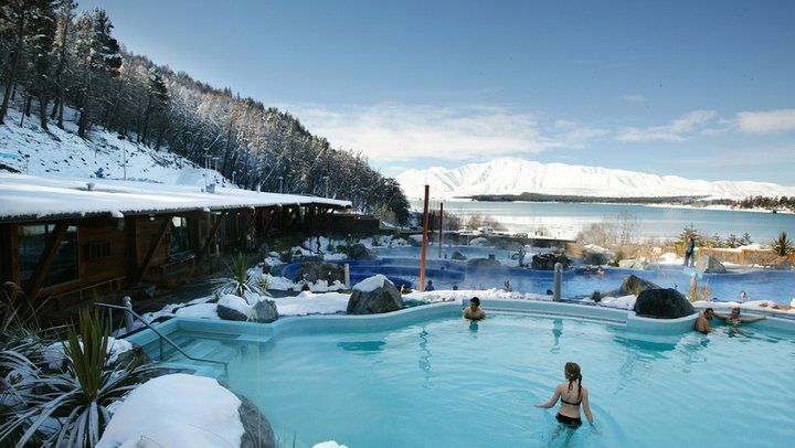 a group of people are swimming in a pool in the snow .
