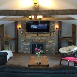 A living room with a fireplace , couch , chairs and a flat screen tv.