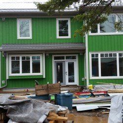 A green house with white windows is under construction.