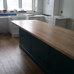 There is a large wooden table in the middle of the kitchen.