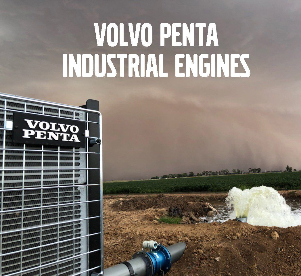 A Volvo Penta industrial engine radiator operates in a field as water sprays from a pipe under a dark, stormy sky.