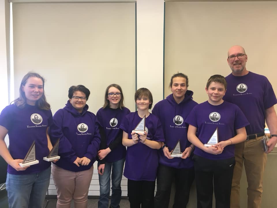 teacher and students holding an award after a math competition