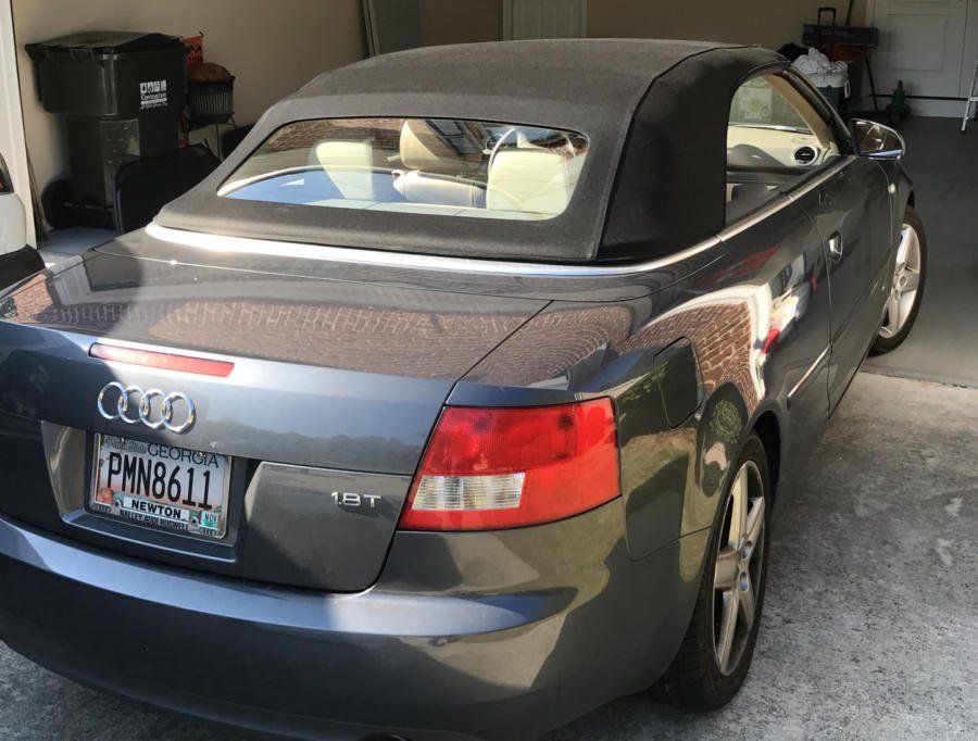 Gray Audi convertible with a black top parked in a garage.